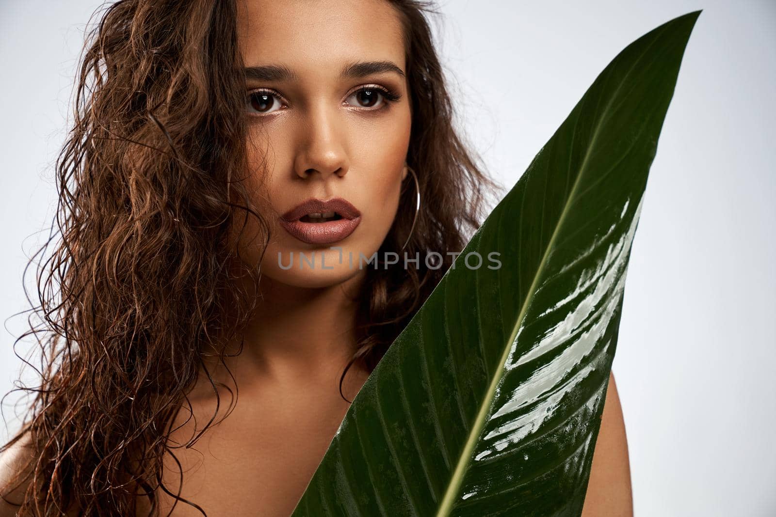 Young woman posing with big green leaf. by SerhiiBobyk