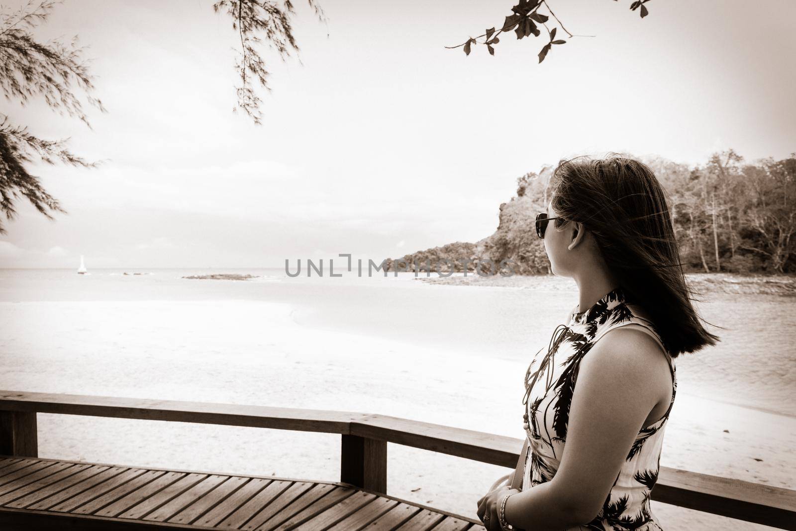 Woman tourist wearing sunglasse looking at the beach and sea in summer on Tarutao island National Park, Satun, Thailand, in two tone black and white color vintage style