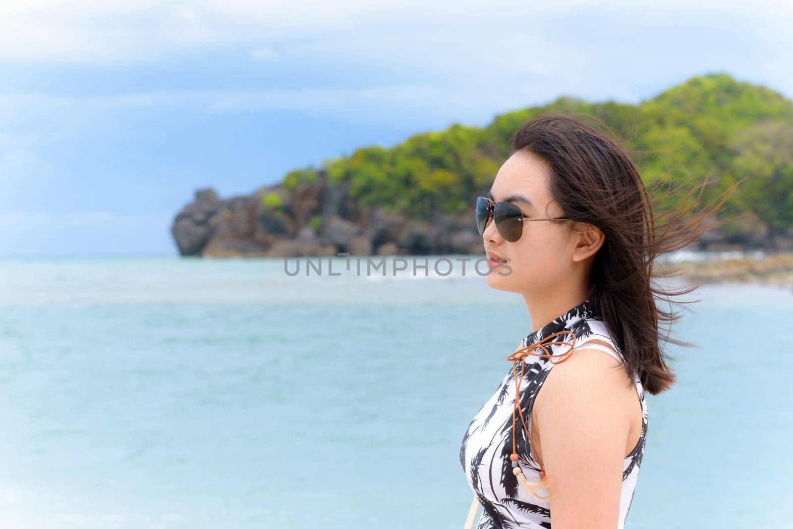 Beautiful woman tourist wearing sunglasse smiling looking at the nature landscape of the beach and the sea in summer sky on Tarutao island National Park, Satun, Thailand