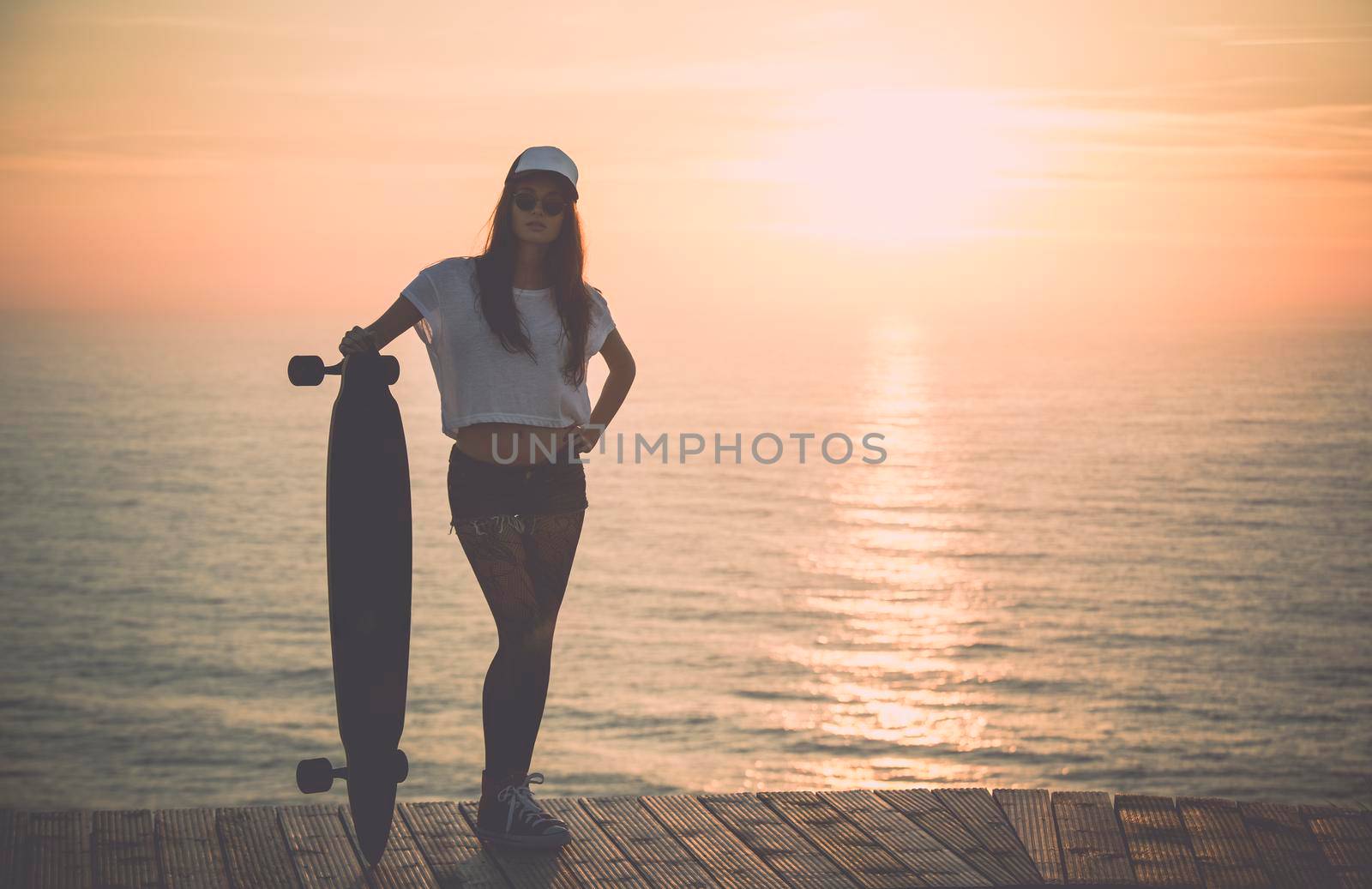 Beautiful fashion skater girl posing with  a skate board