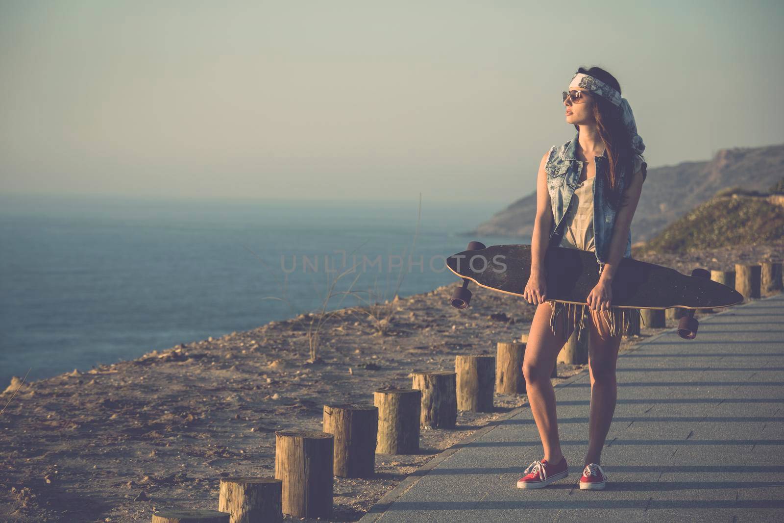 Beautiful and fashion young woman posing with a skateboard