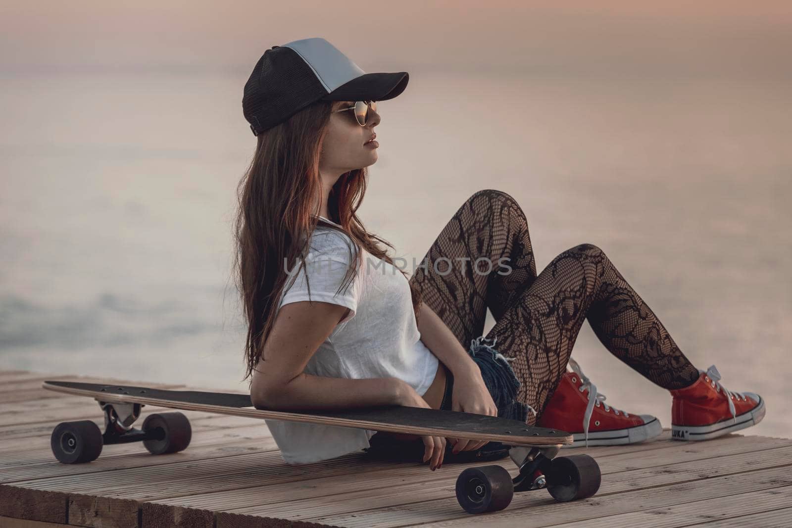 Beautiful and fashion young woman posing with a skateboard