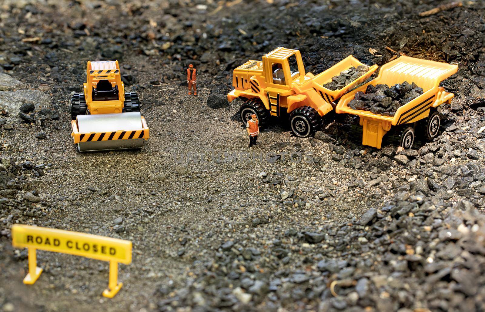 Toy workers in road construction diorama load rocks into haul truck.