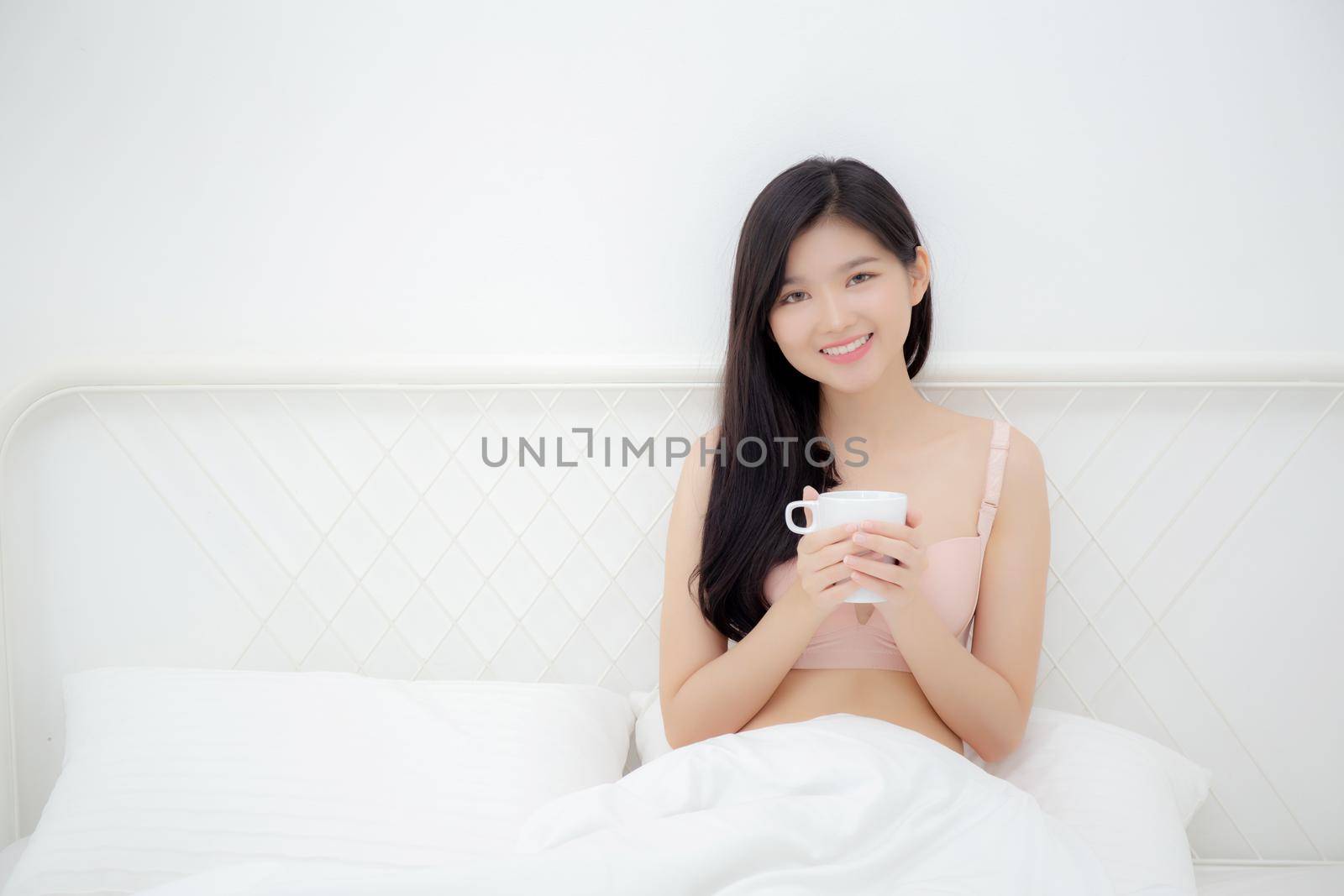 Beautiful young asian sexy woman in underwear drinking coffee in the morning on bed at bedroom, asia girl with seductive figure fit drinking beverage for relax after wake up, lifestyle concept.
