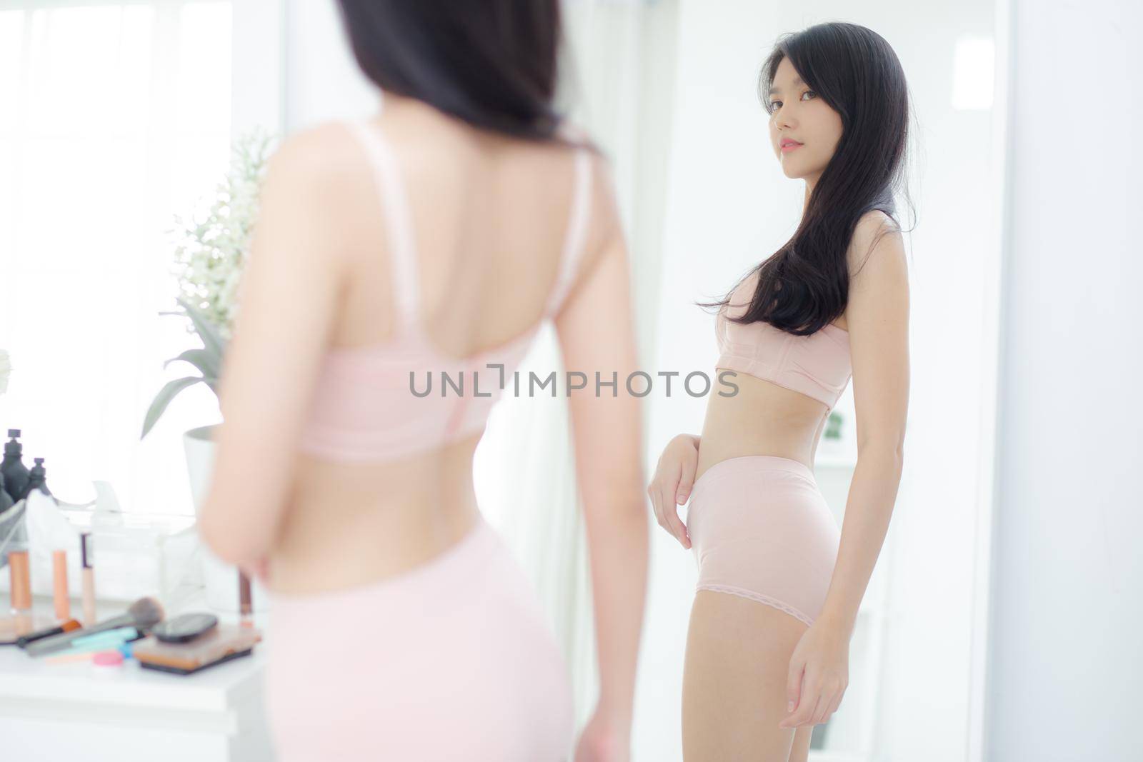Lifestyle of beautiful young asian woman in underwear looking in mirror with belly figure slim at home, beauty body girl in lingerie shape fit with weight loss, abdomen and waist sexy perfect.