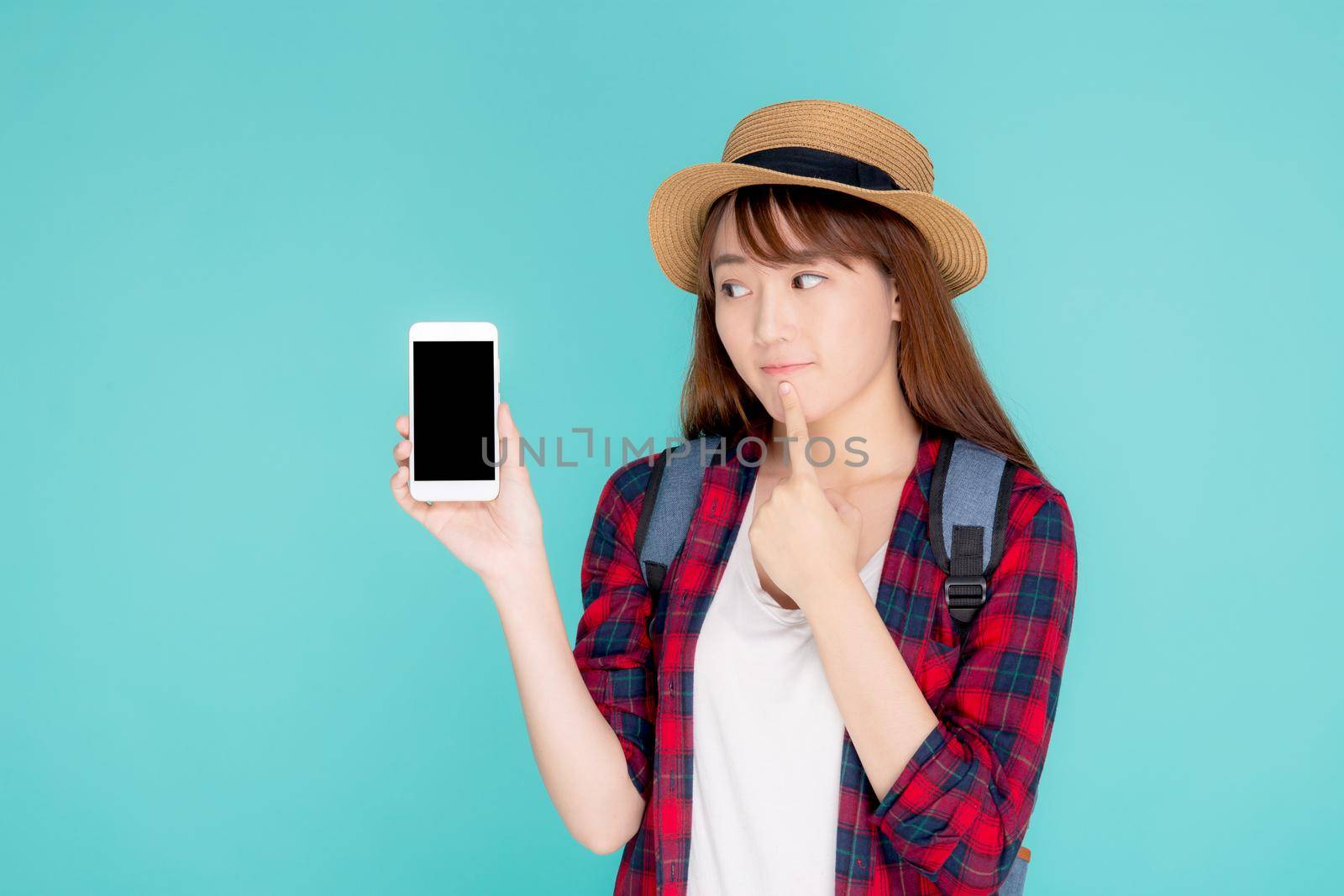 Beautiful young asian woman showing smart mobile phone for presenting something in travel summer trip in vacation isolated on blue background, asia girl holding smartphone and thinking idea.