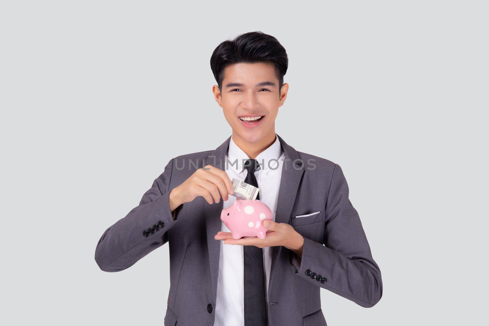 Young asian businessman in suit deposit money dollar with piggy bank isolated on white background, business man saving with planning budget and finance for success investment and financial.