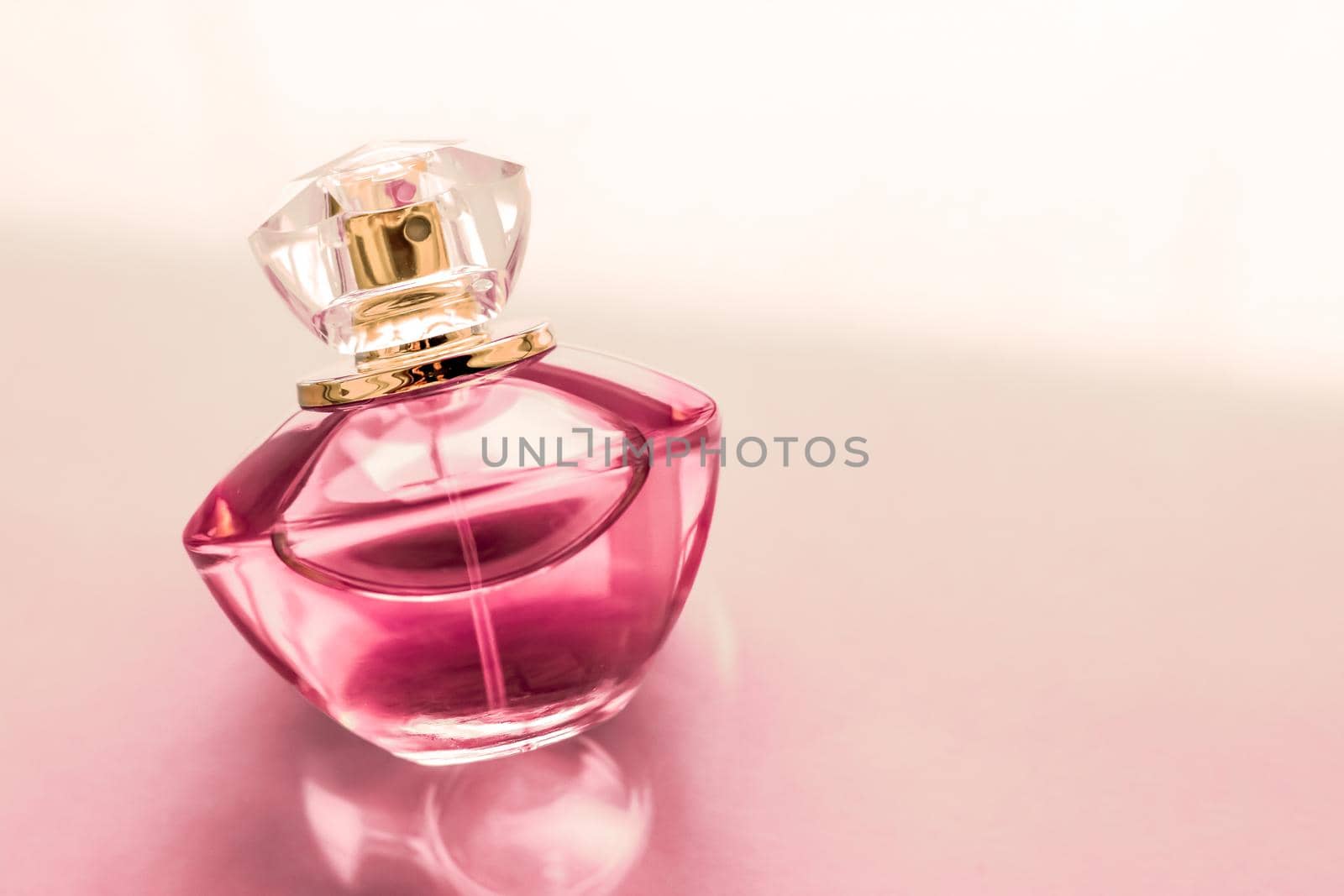 Perfumery, spa and branding concept - Pink perfume bottle on glossy background, sweet floral scent, glamour fragrance and eau de parfum as holiday gift and luxury beauty cosmetics brand design