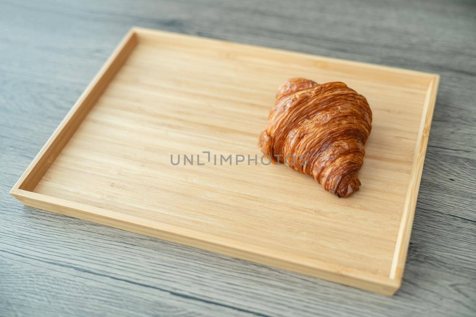 Serving baked crispy croissants on wooden tray.