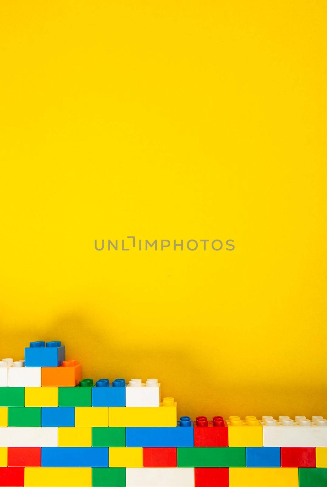 Plastic building blocks on yellow background