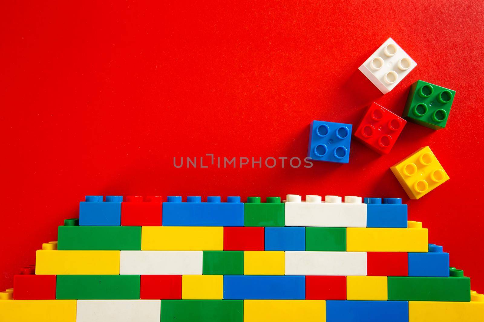 Color plastic building blocks on red background by tehcheesiong