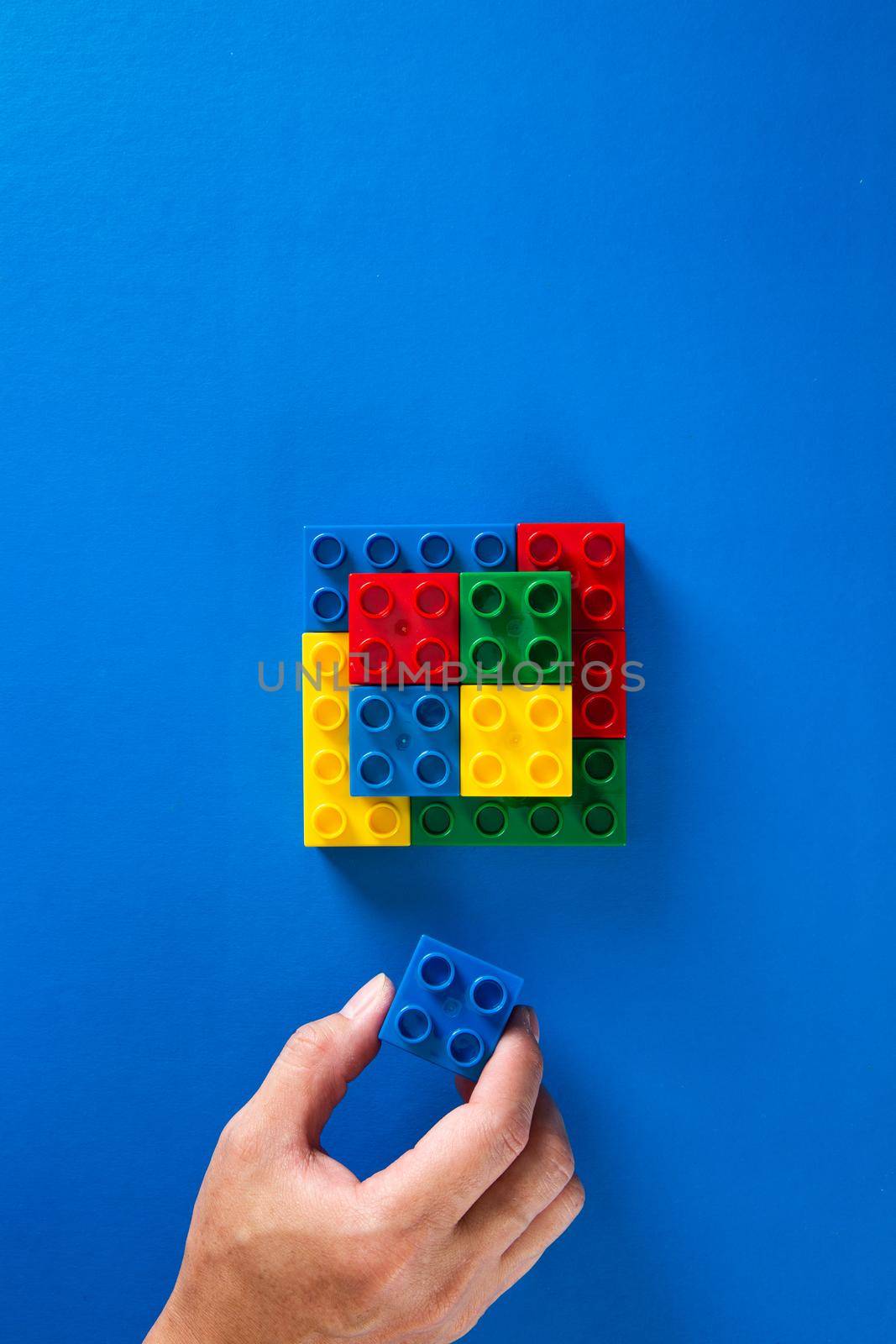 hand stacking up the colorful plastic block