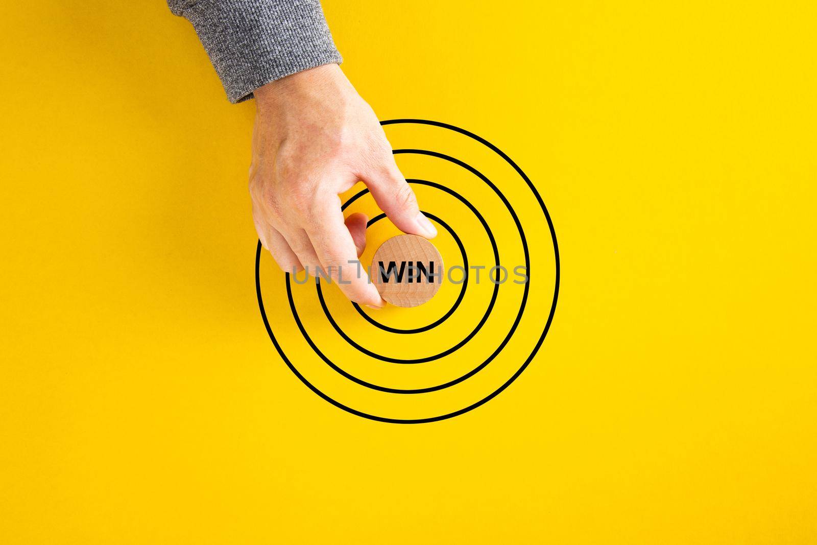 businessman hand put round block with Win word aim at concentric circles of marketing target.