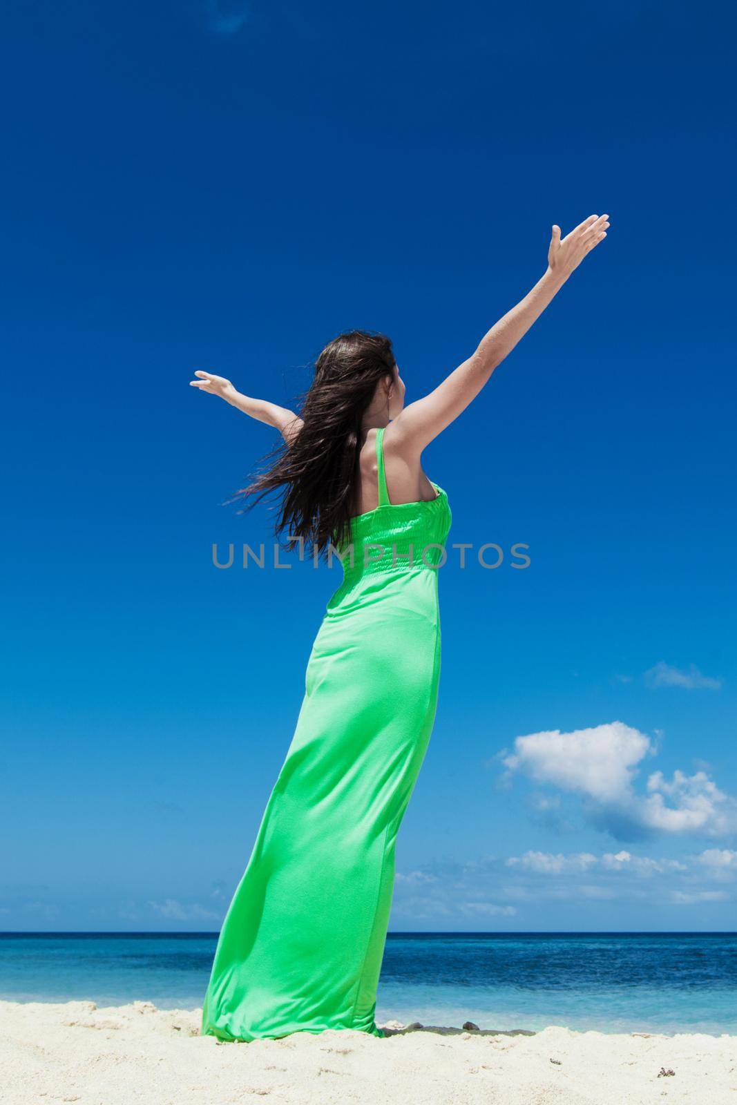Happy woman enjoy summer vacation on beach standing with raised hands