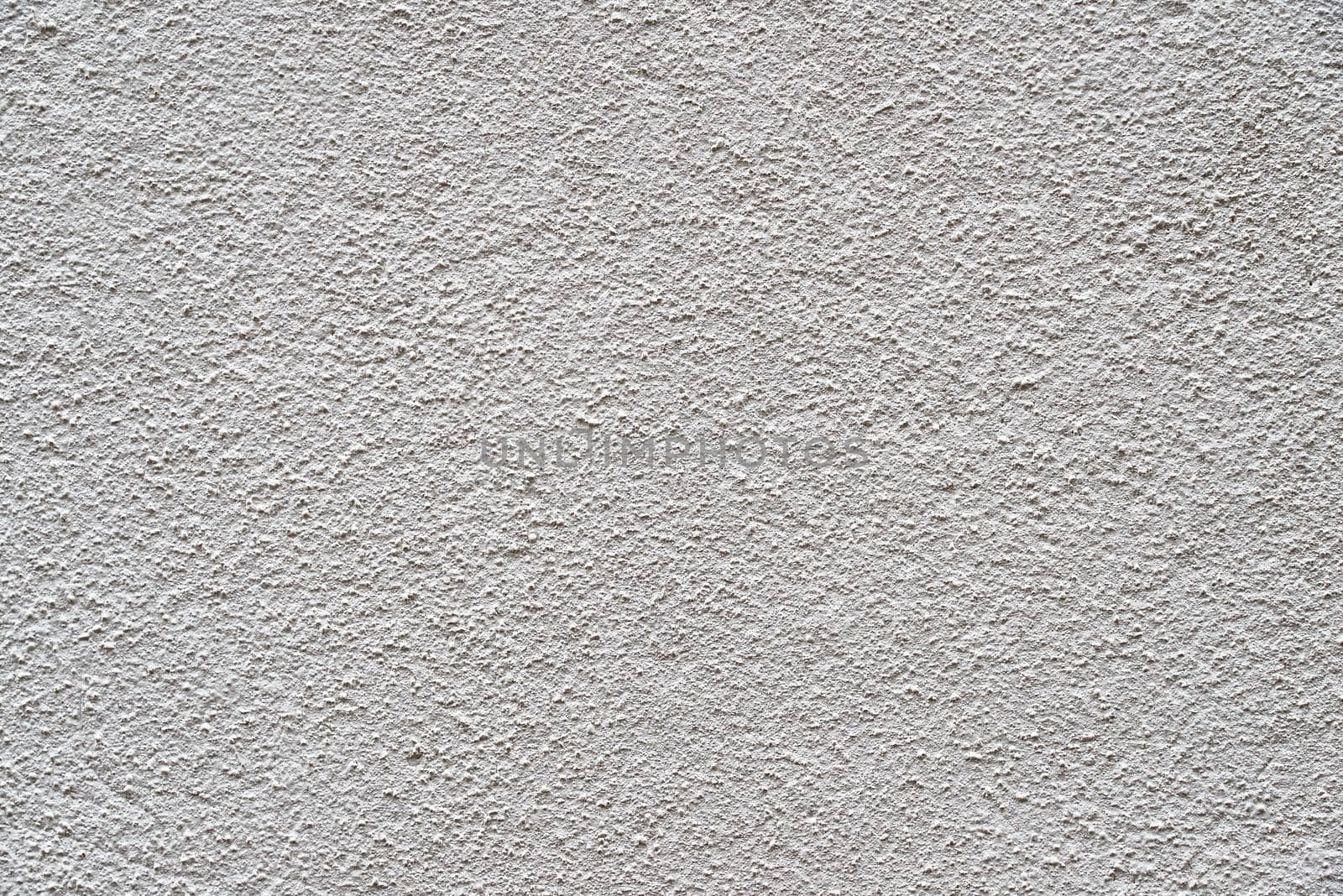 The heavy surface texture of an external wall covered in white plaster.