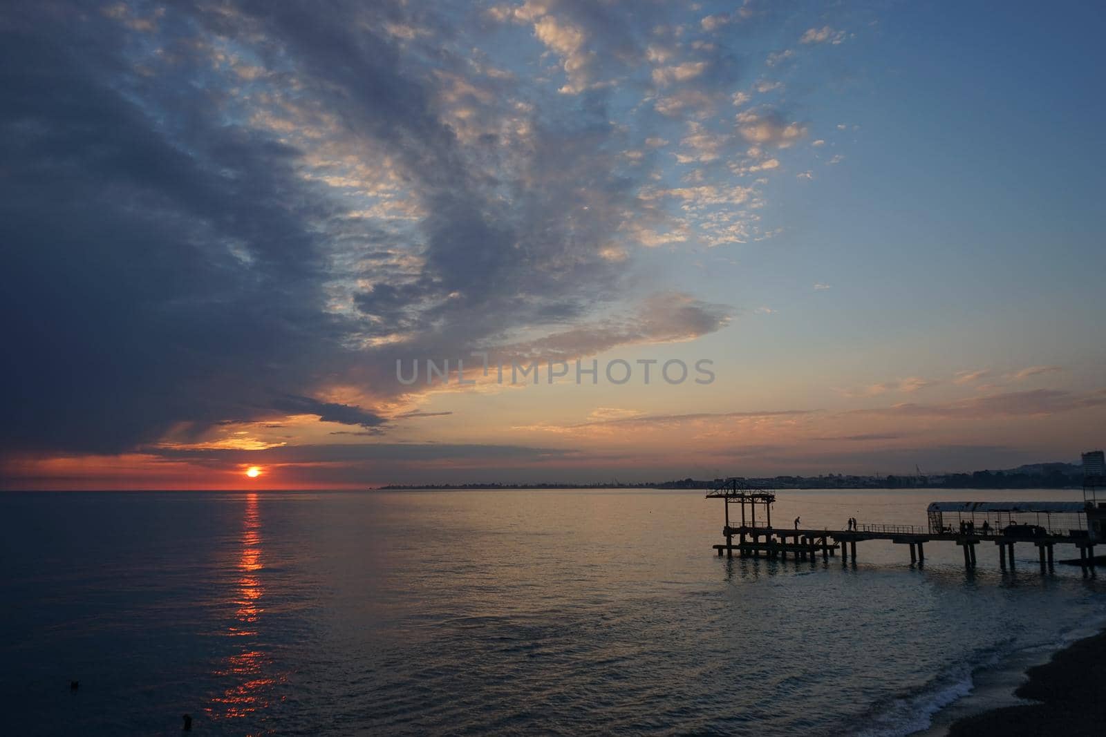 dramatic sunset with dark clouds over the calm sea.