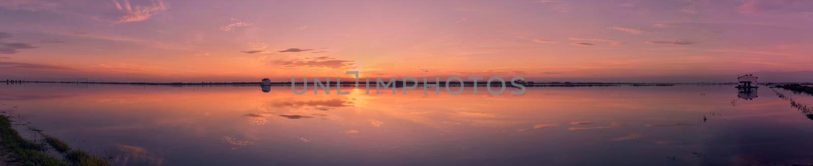 Sunset on the lake, with clouds. Rustic houses, vegetation, sun. long exposure, Albufera Valencia. Panoramic photo