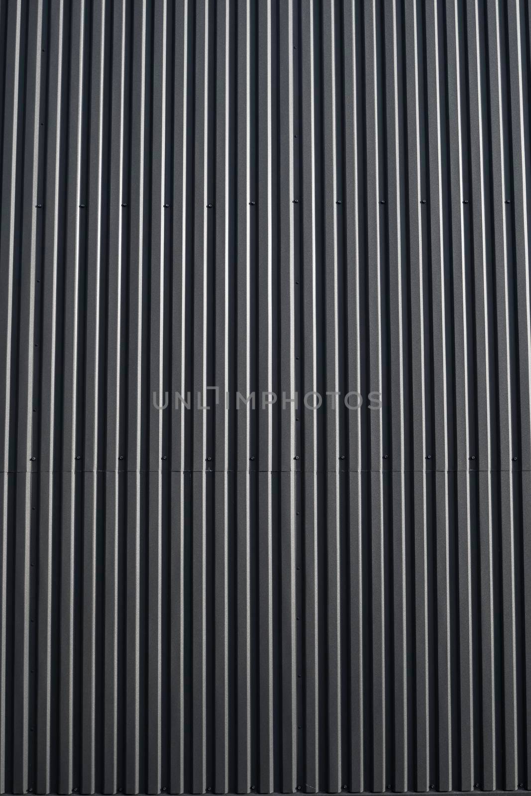Black corrugated iron sheet used as a facade of a warehouse or factory. Texture of a seamless corrugated zinc sheet metal aluminum facade. Architecture. Metal texture. by vovsht