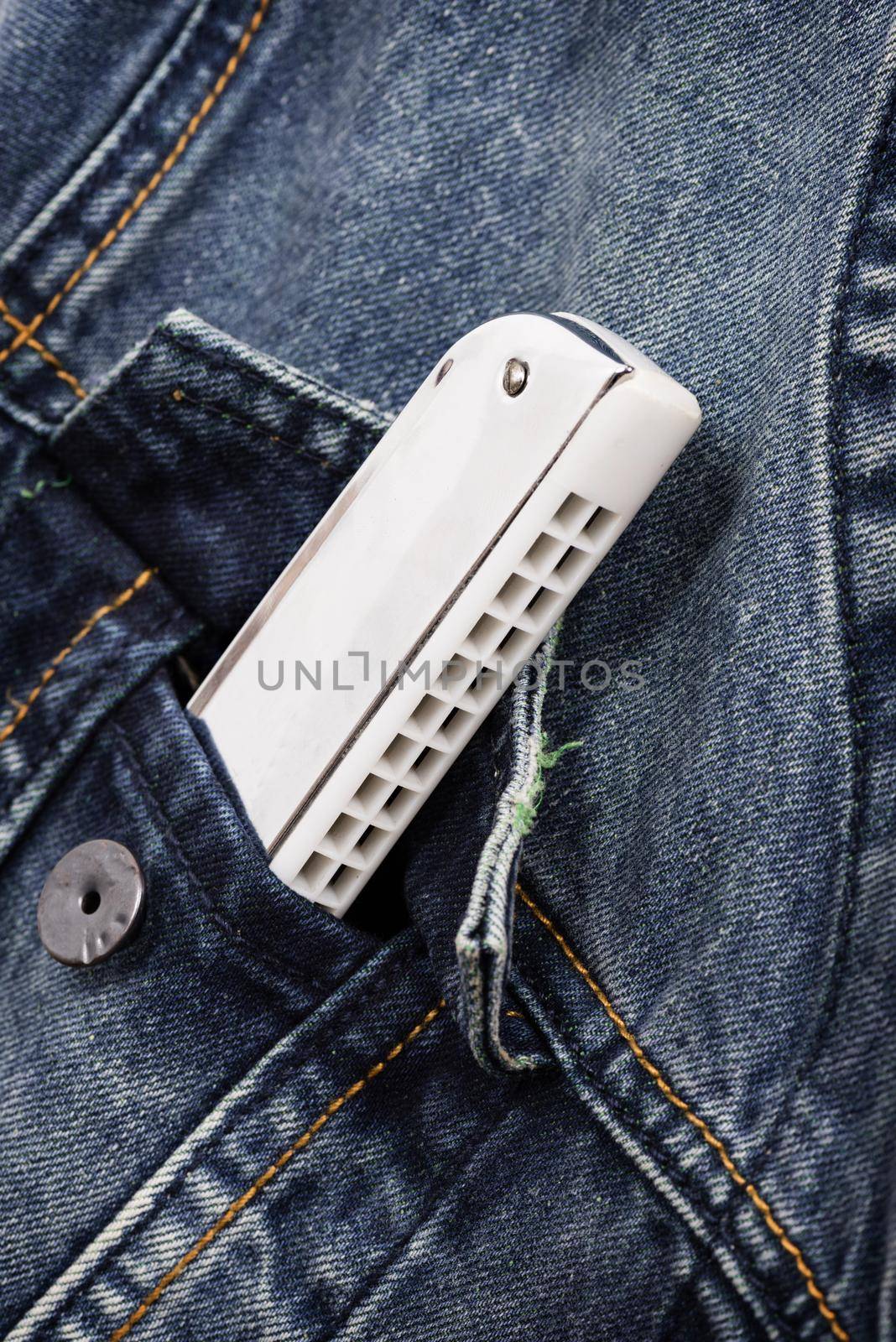 isolate silver/white harmonica in denim pocket, music instrument