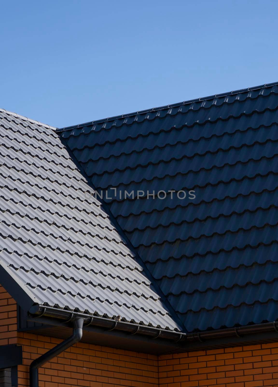 Grey corrugated metal profile roof installed on a modern house. The roof of corrugated sheet. Roofing of metal profile wavy shape. Modern roof made of metal. Metal roofing