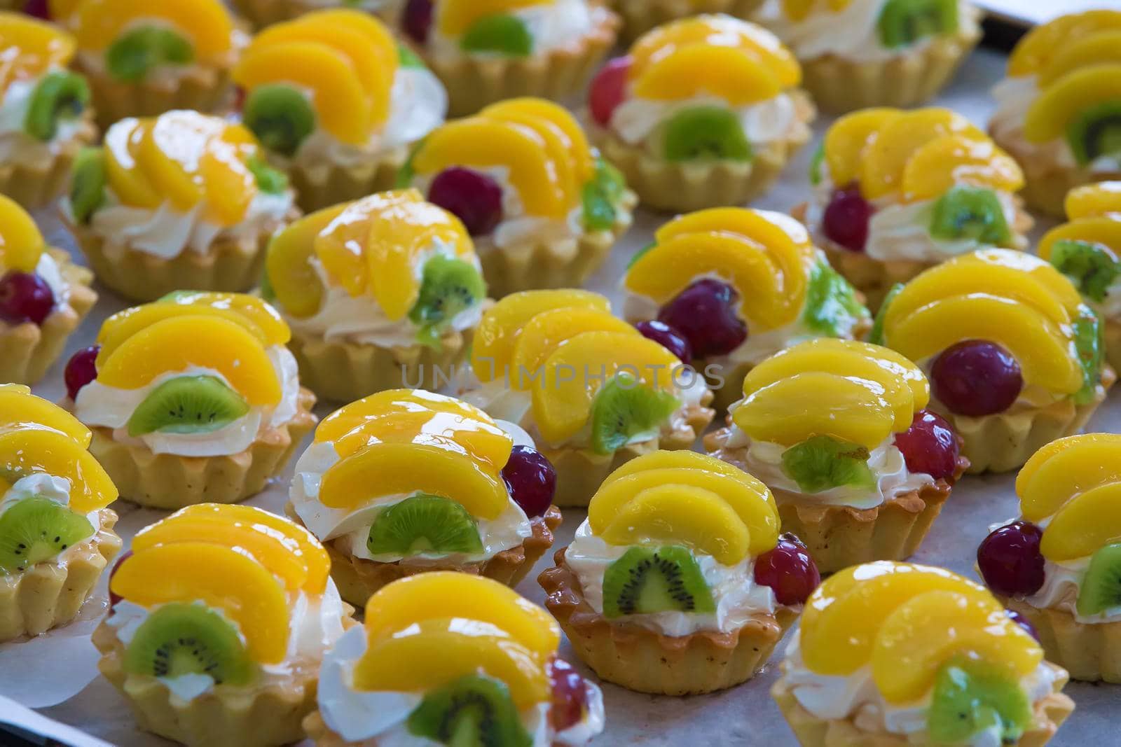 Cupcakes with cream and fruit.Cupcakes with cream and fruit peach kiwi and cherries. A lot of baking