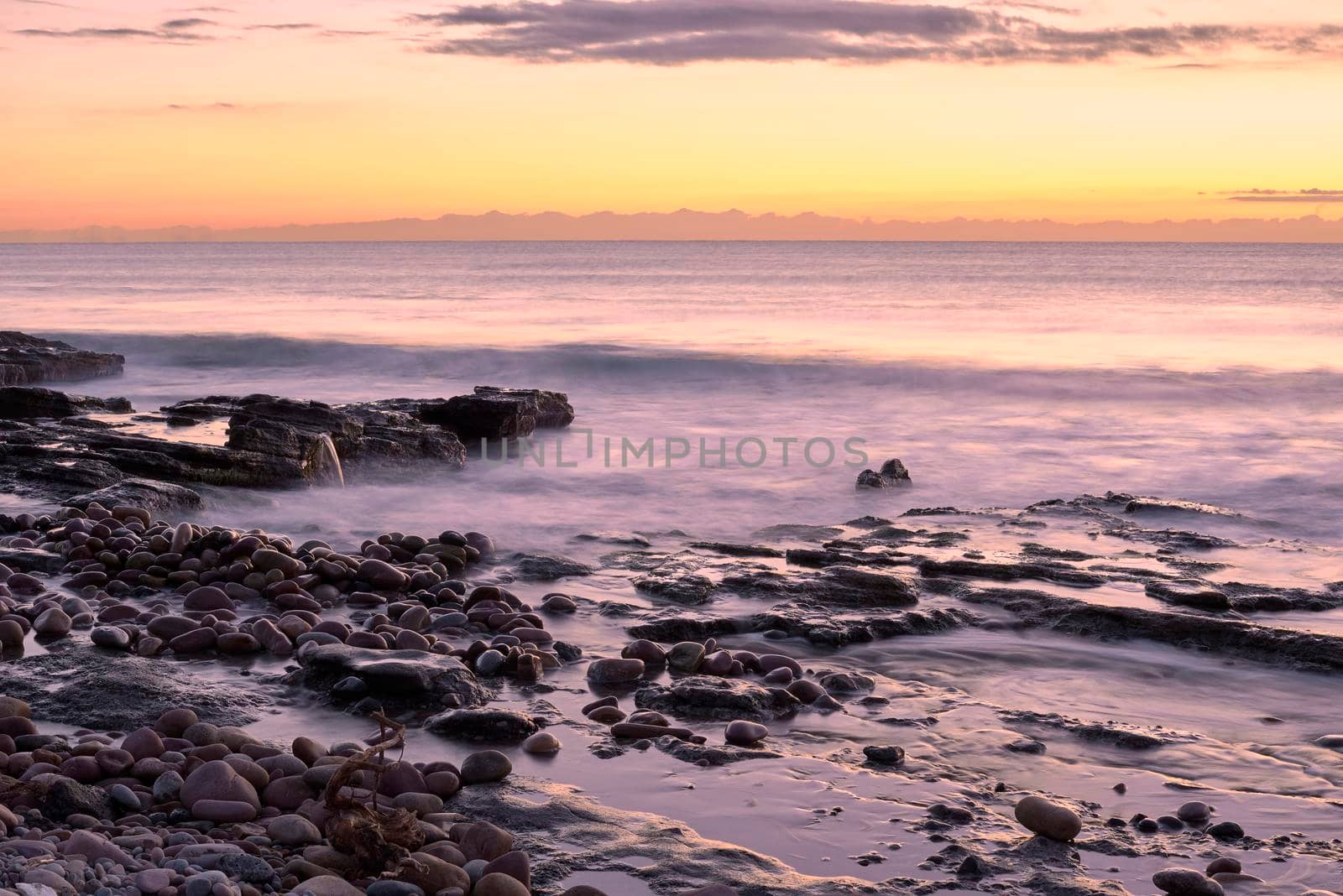 Sunrise on the rocky beach, long exposure, water silk effect