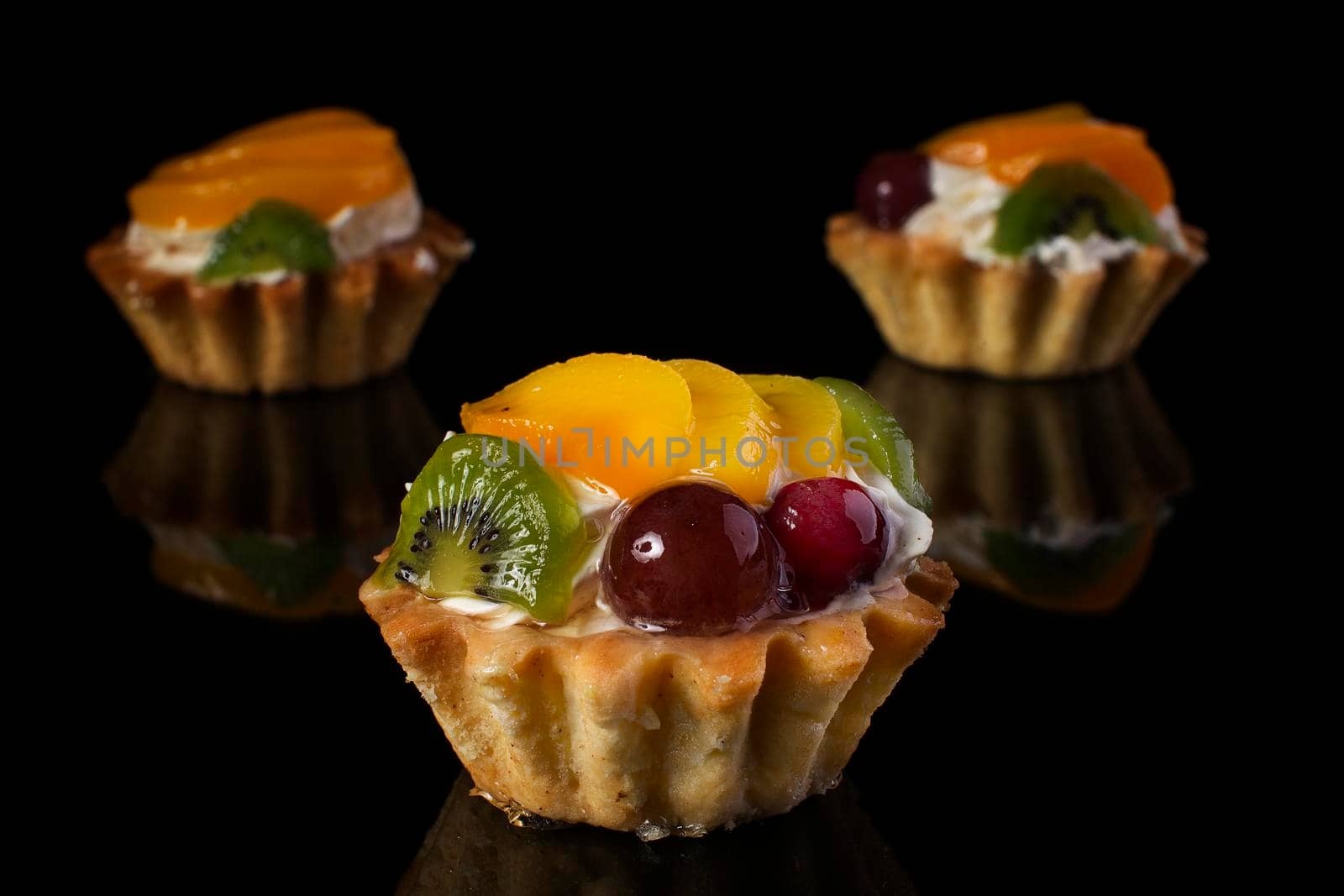 cake basket with kiwi fruit peach gooseberries close-up on a black background