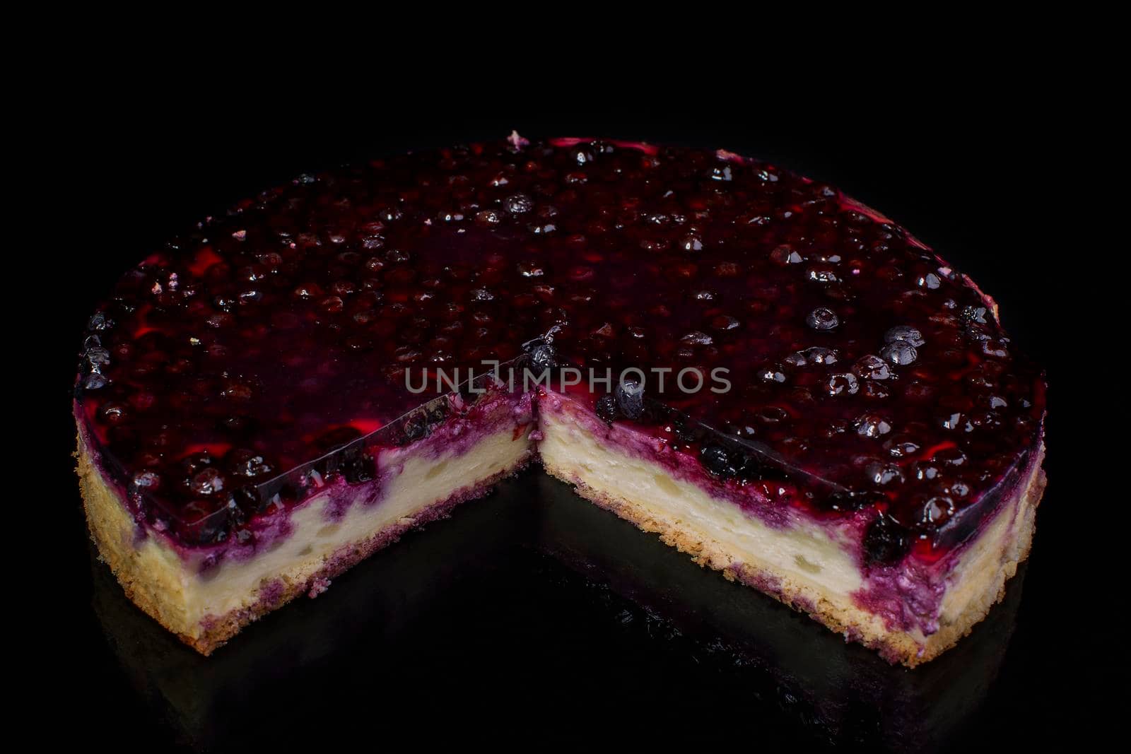 Piece of cake cheesecake with currant in jelly on black background