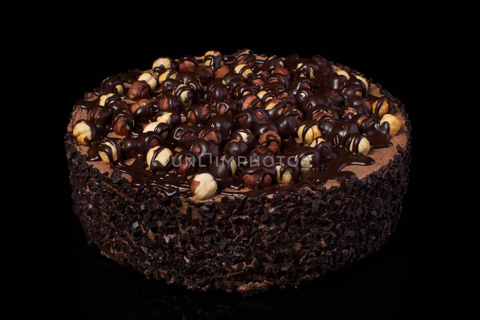 Chocolate cake with hazelnuts with white cream on a black background closeup