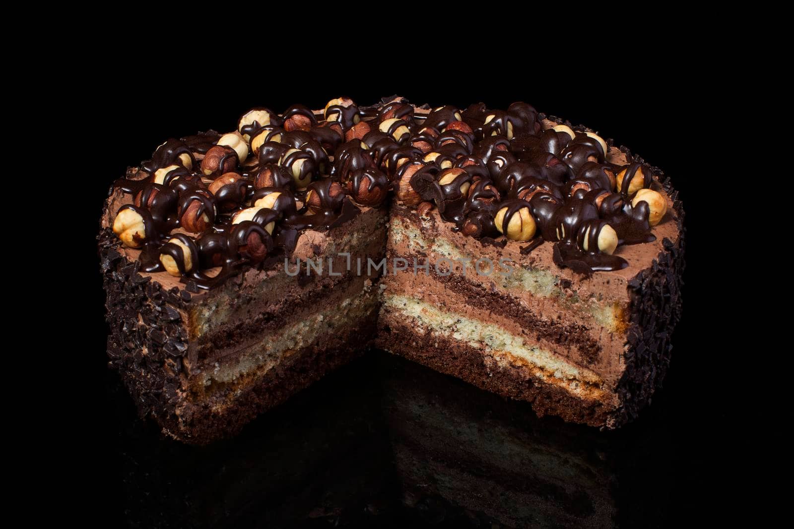 A piece of chocolate cake with hazelnut with white cream on a black background