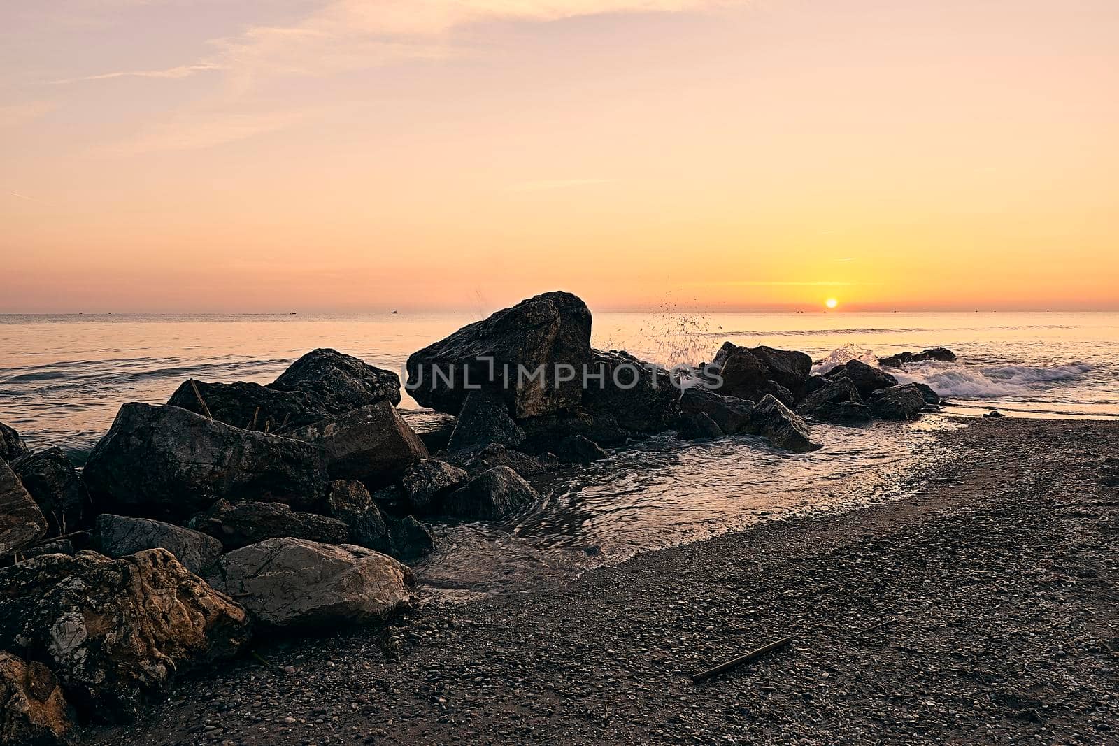 Sunrise on the beach in front of some rocks by raul_ruiz
