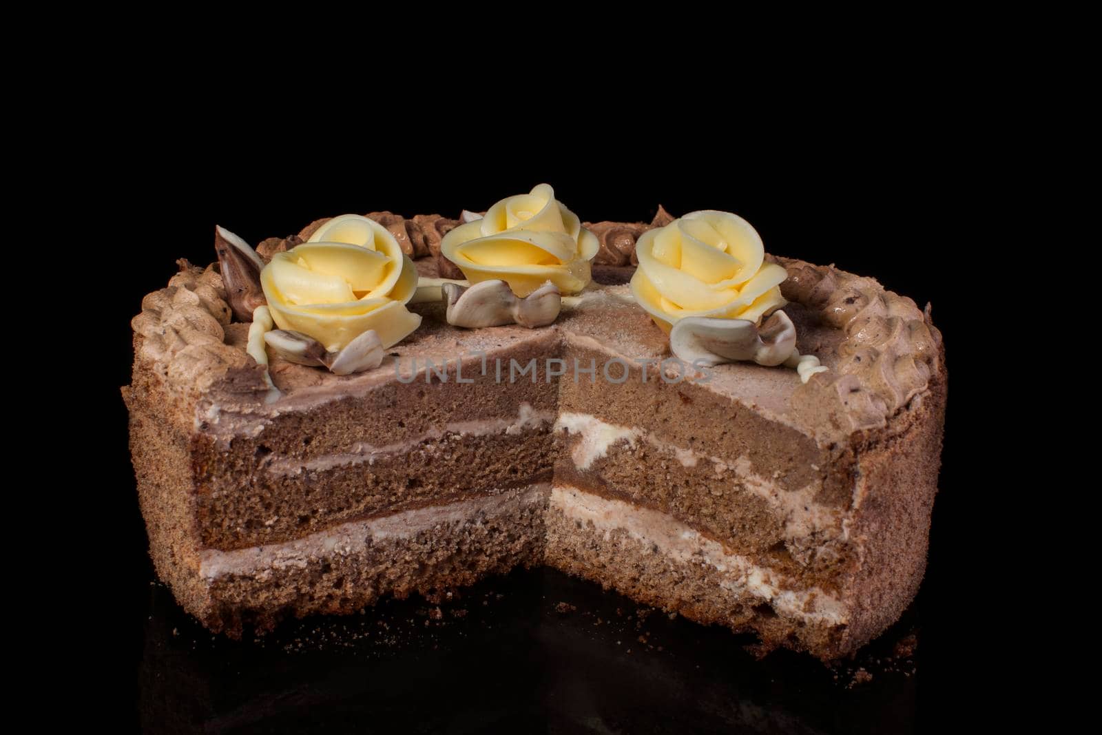 Chunk of chocolate cake decorated with oil cream on a black background