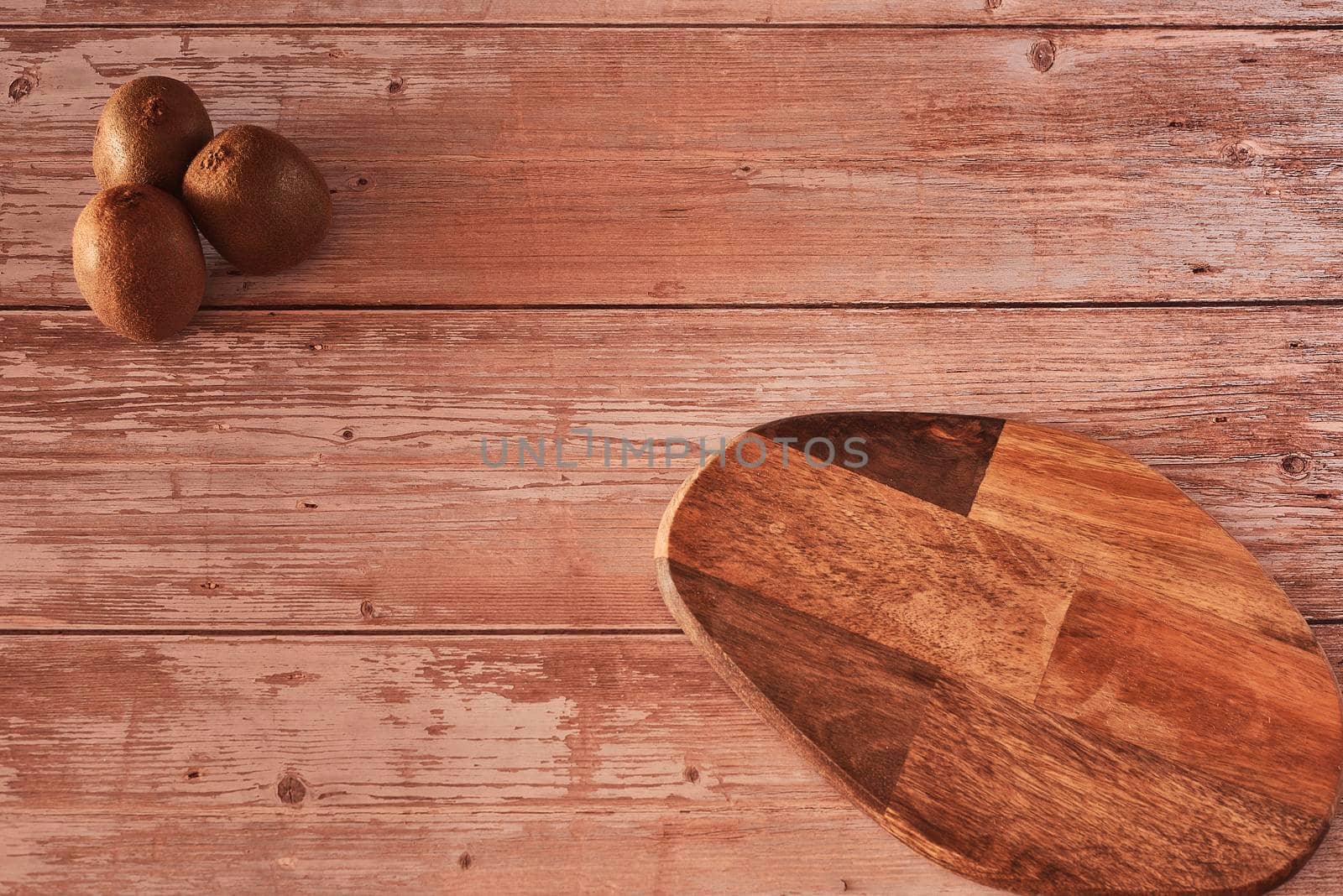 Several kiwis on wooden board. Wooden boards, zenithal view, free space, white bowl