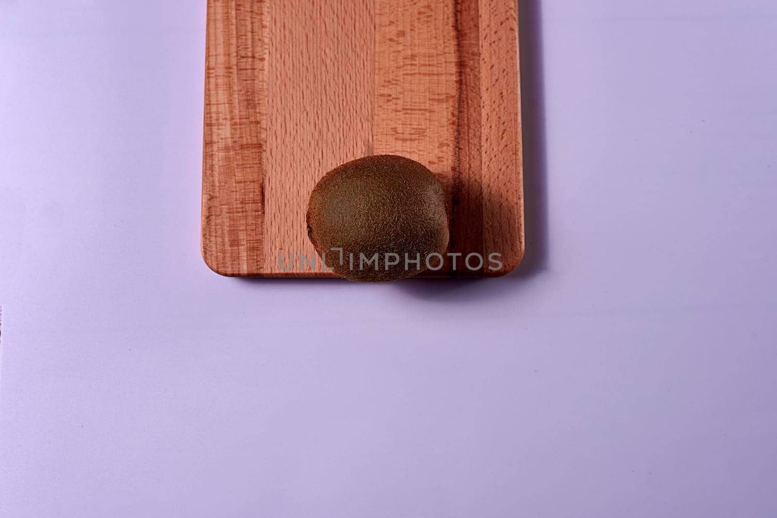 Kiwi on wooden board. Blue background, unique, free space, zenithal view
