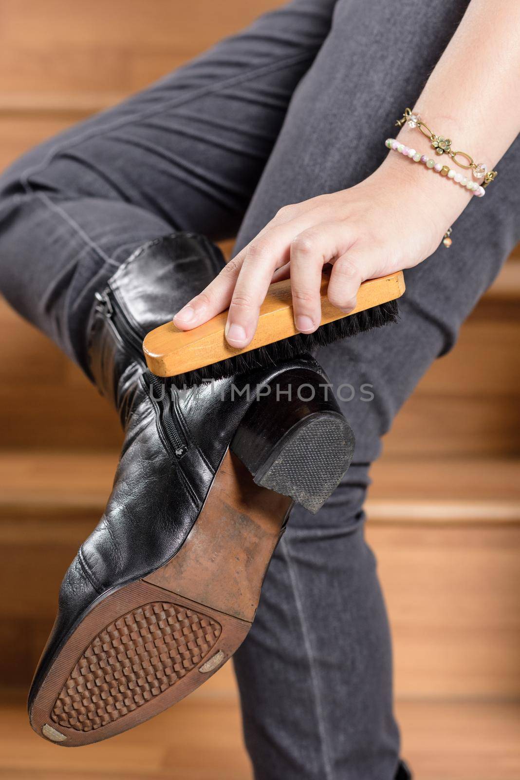 young woman cleaning her black leather boots