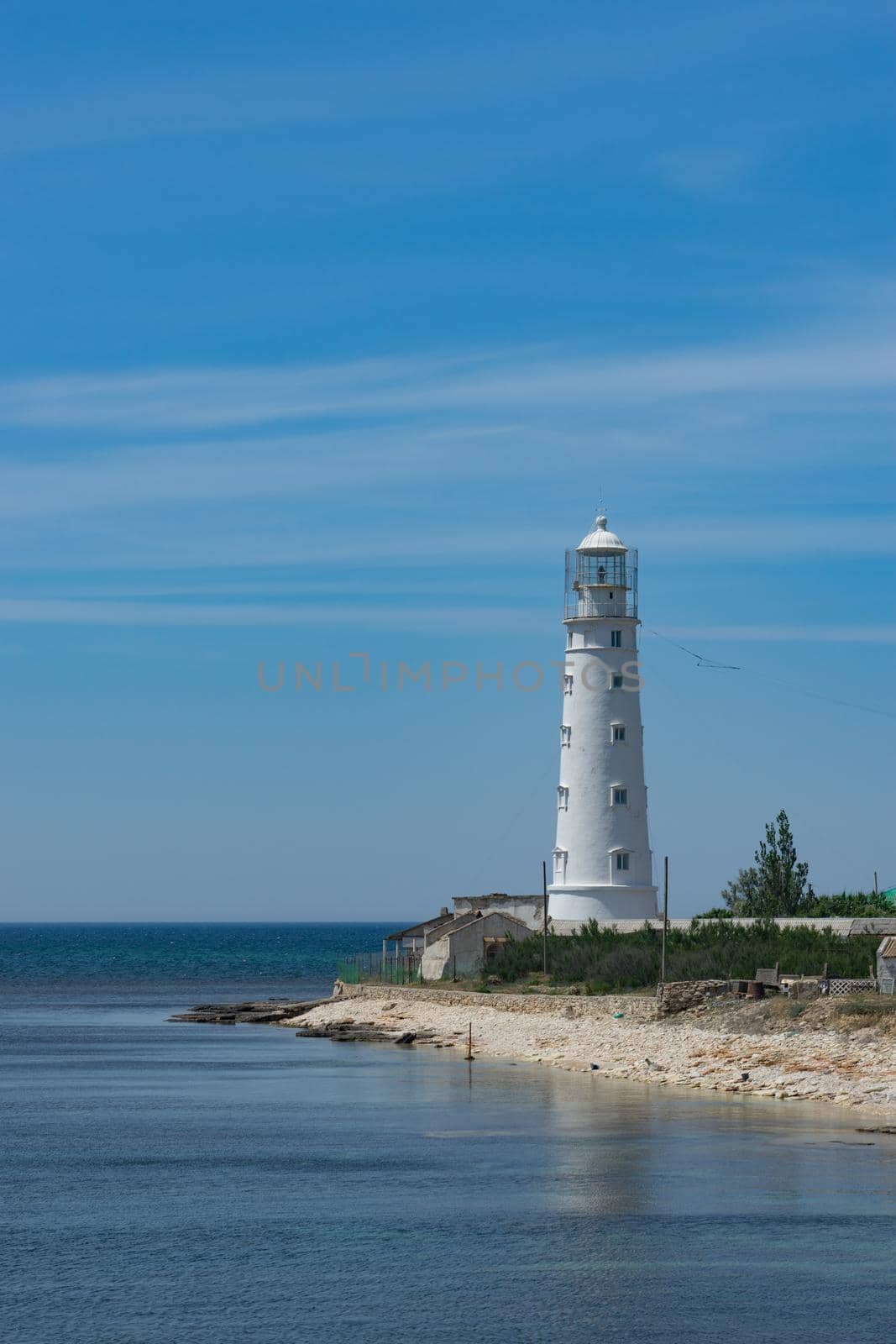seascape with beautiful white lighthouse on blue sky background. by Vvicca
