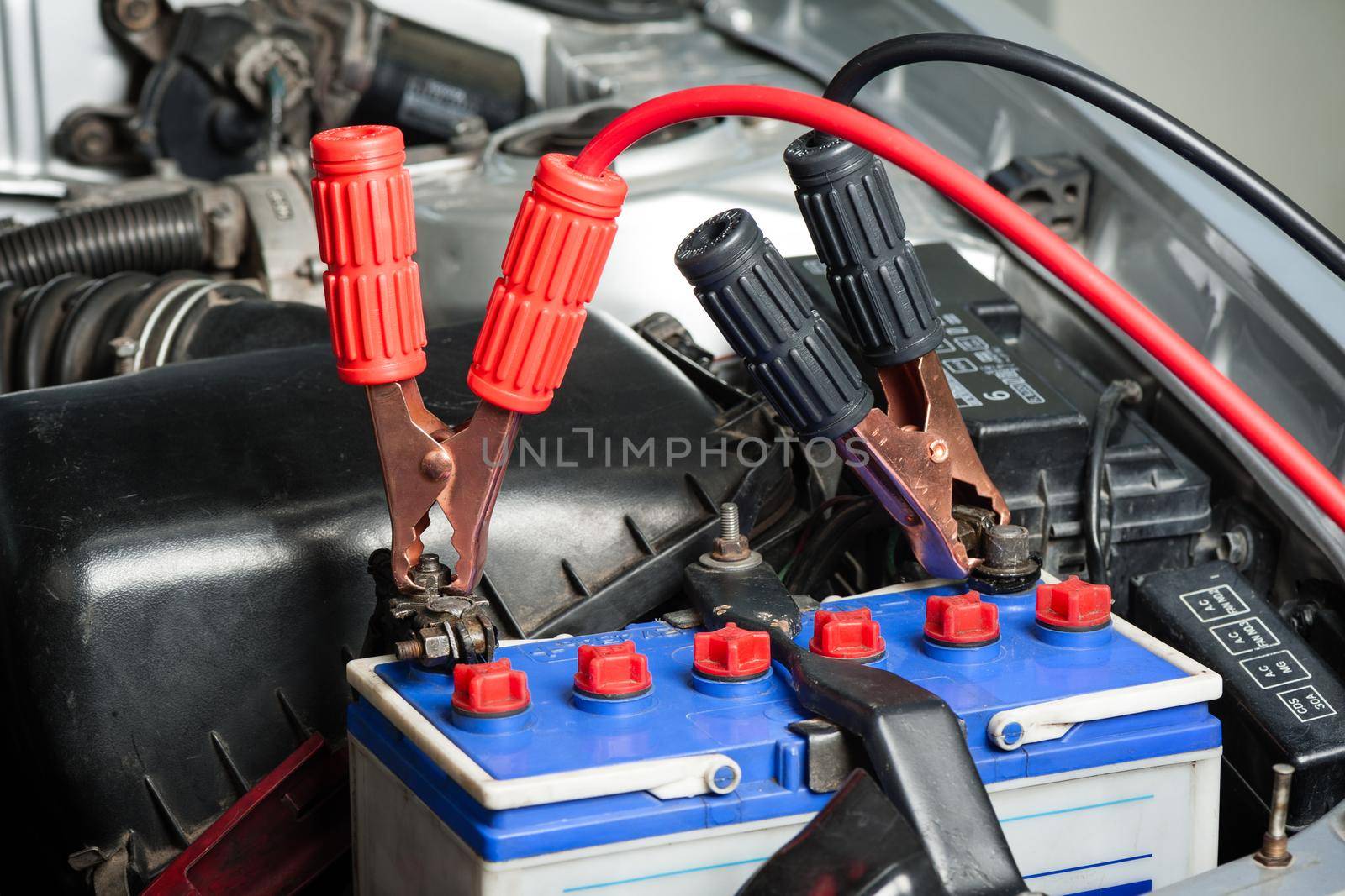 car battery with jumper cable in engine room, car repairing concept