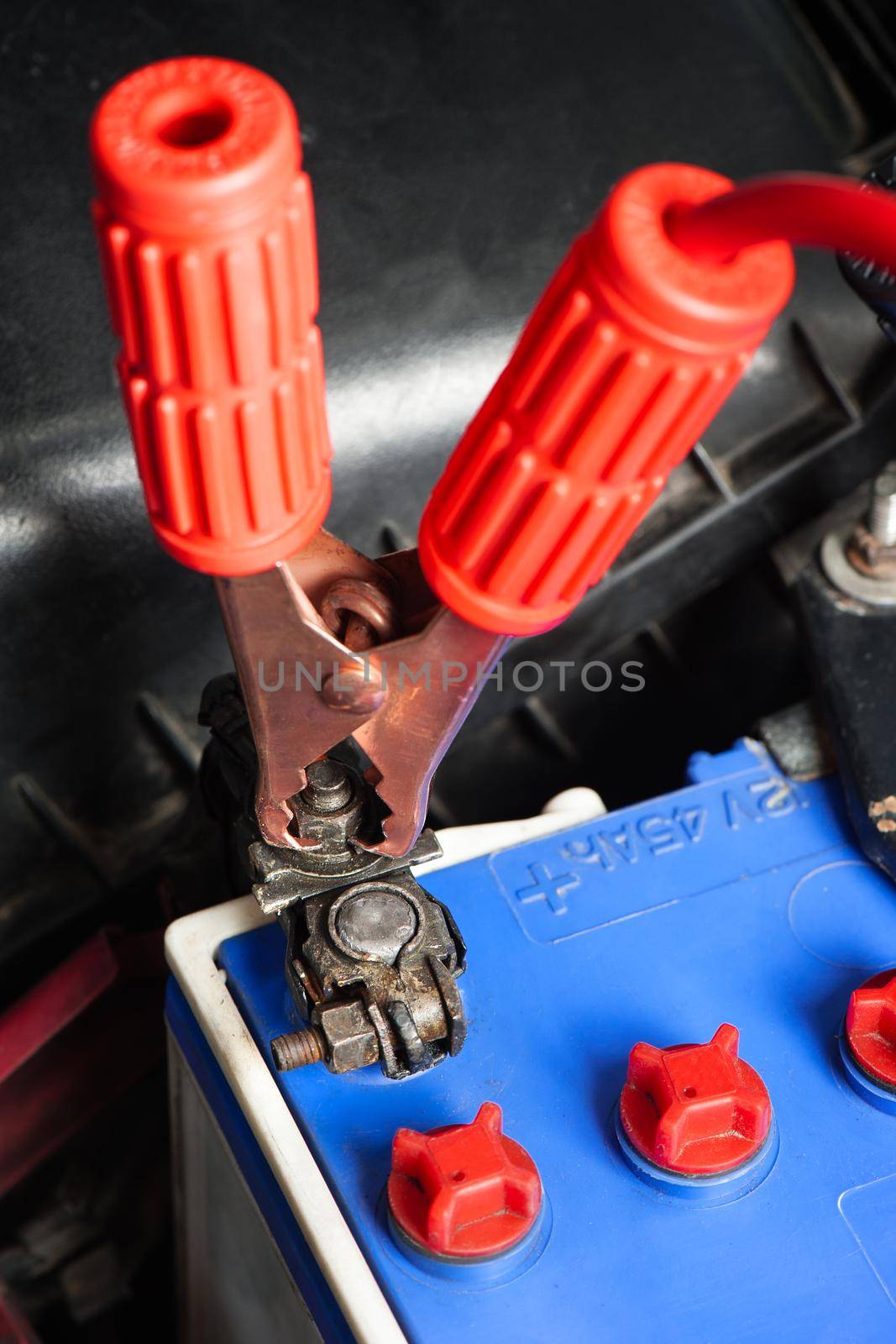 car battery with jumper cable in engine room, car repairing concept