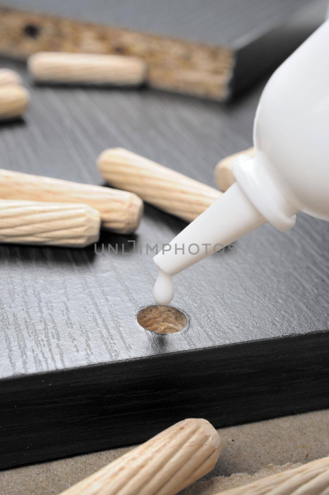 inserting glue to the hole on black particleboard