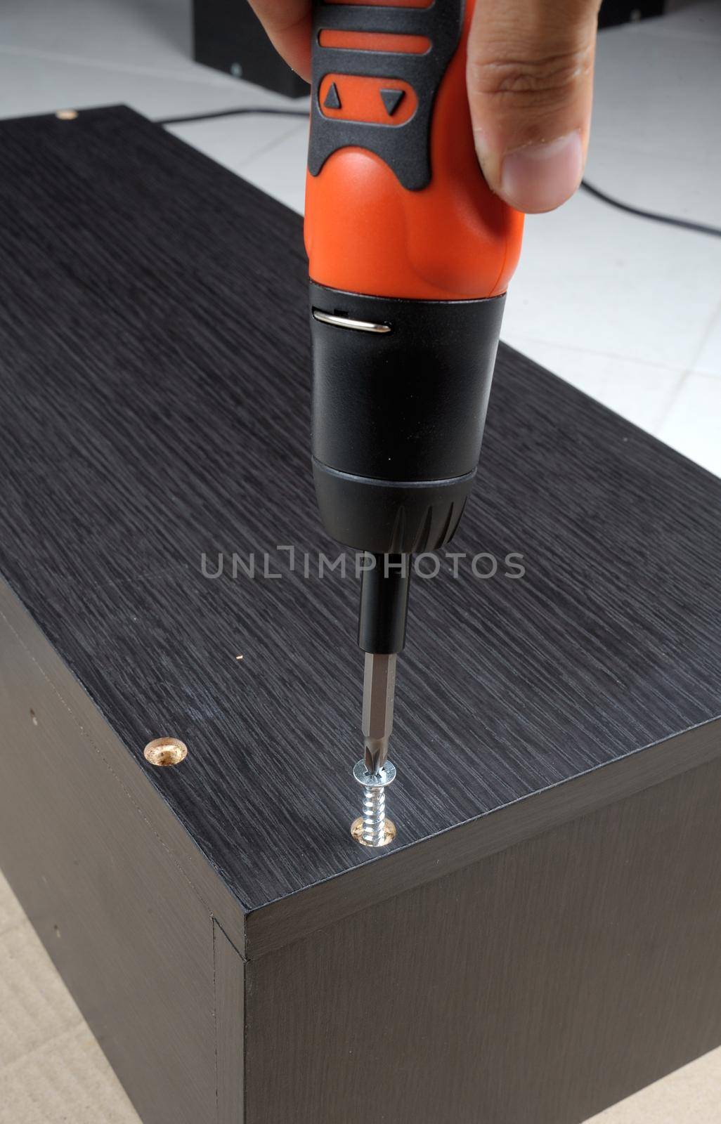 worker screws in a wooden furniture with a screwdriver