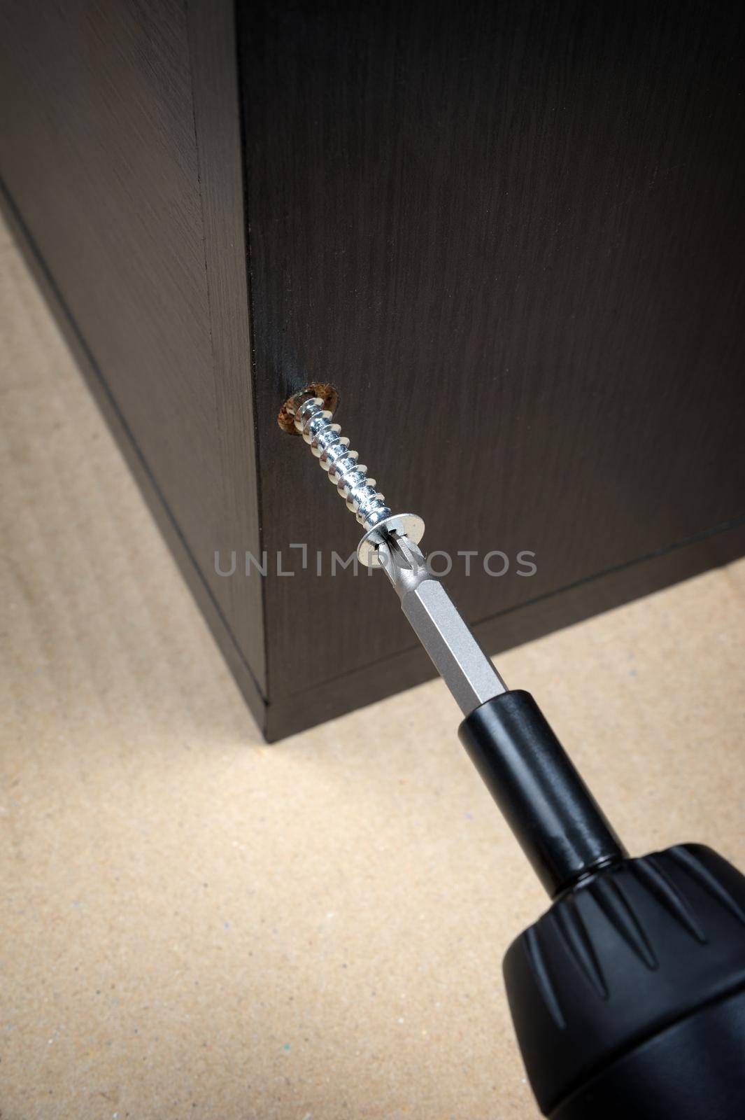 worker screws in a wooden furniture with a screwdriver