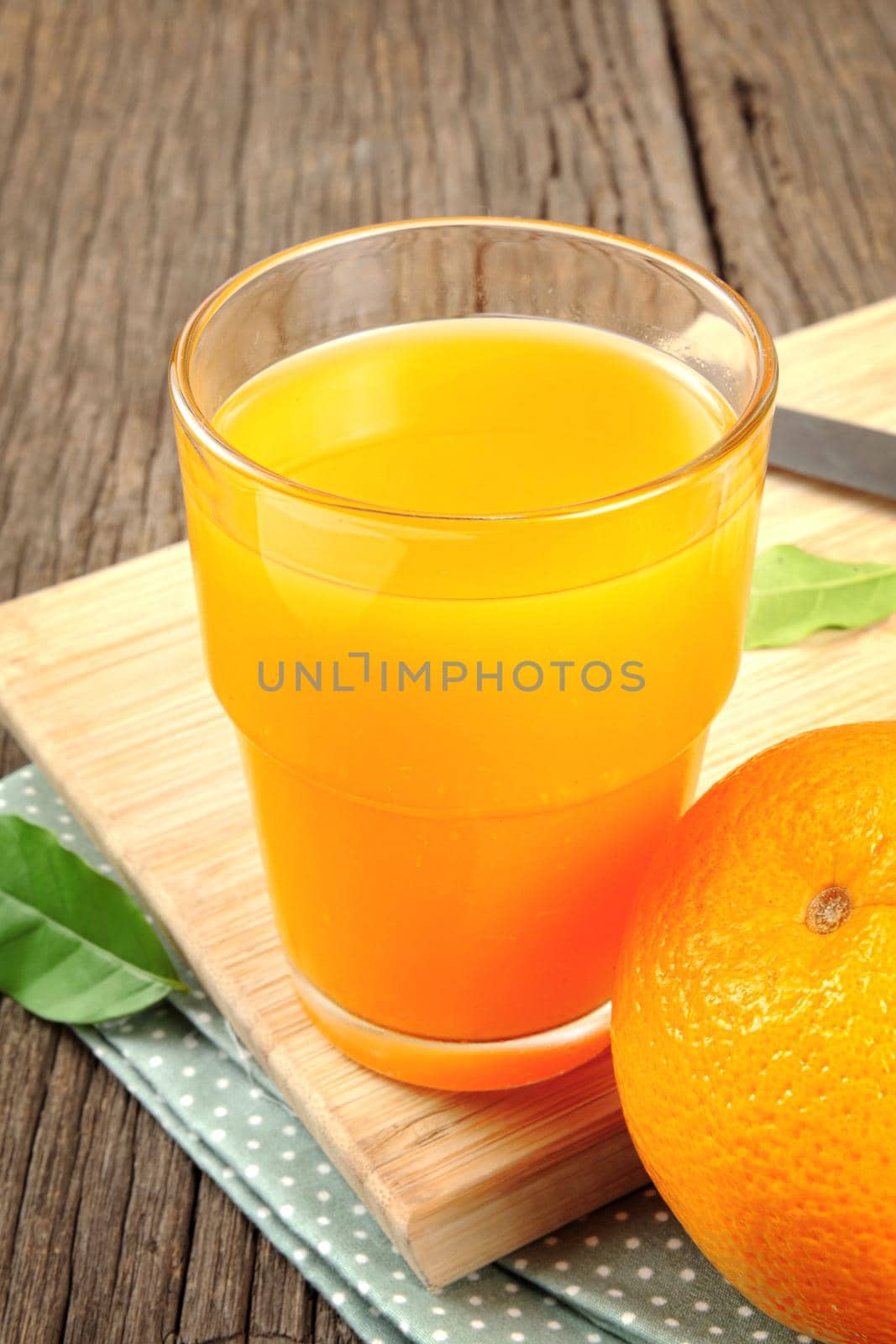 Ripe orange and cup of orange juice on wooden table