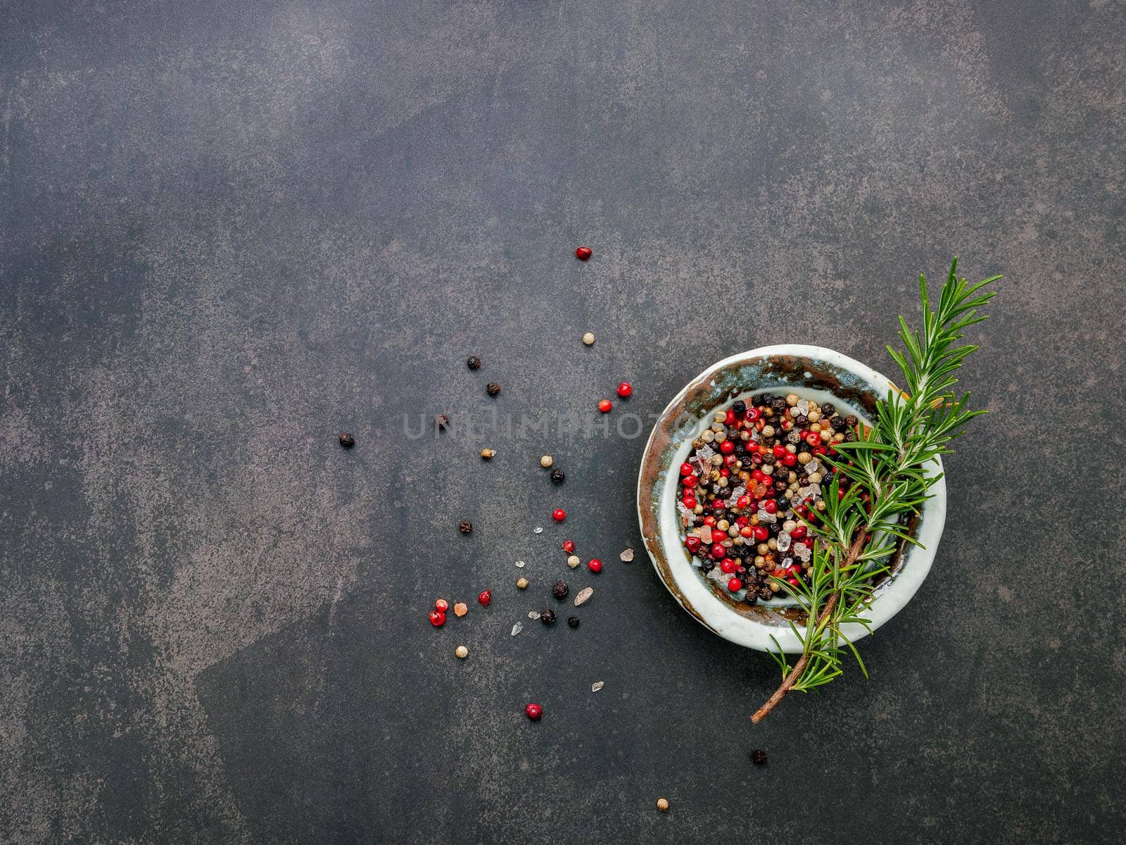 Ingredients for steak seasoning in ceramic bowl set up on dark concrete background with copy space.