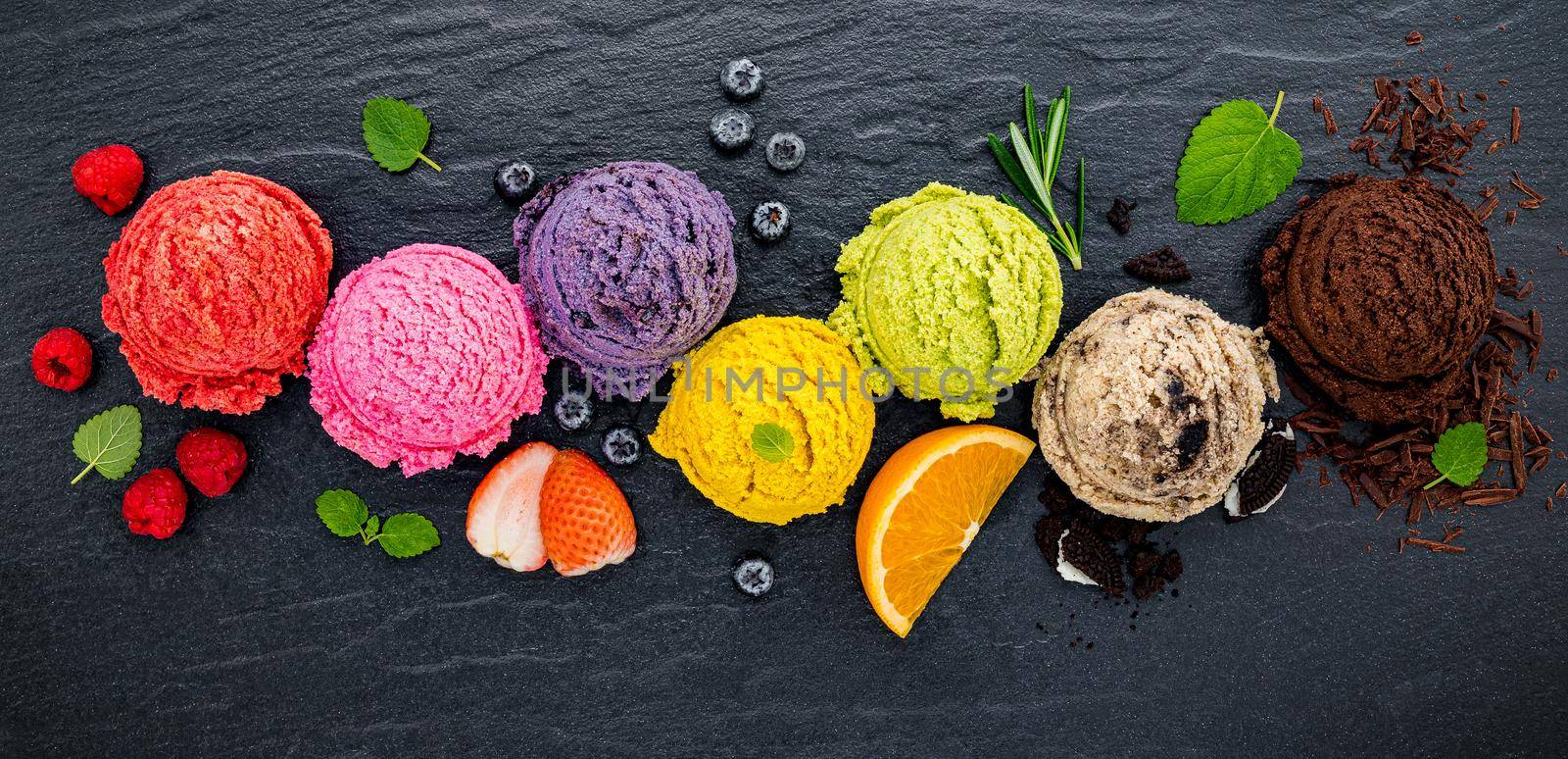 Various of ice cream flavor ball blueberry ,lime ,pistachio ,almond ,orange ,chocolate and vanilla set up on dark stone background . Summer and Sweet menu concept. by kerdkanno
