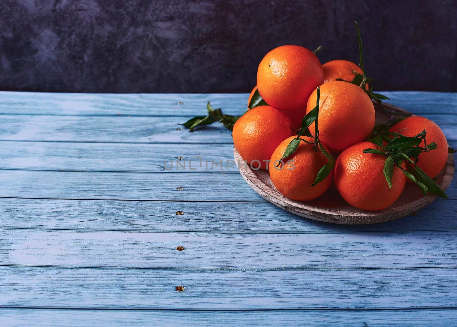 A plate with several oranges on marble background and wooden floor, Empty space