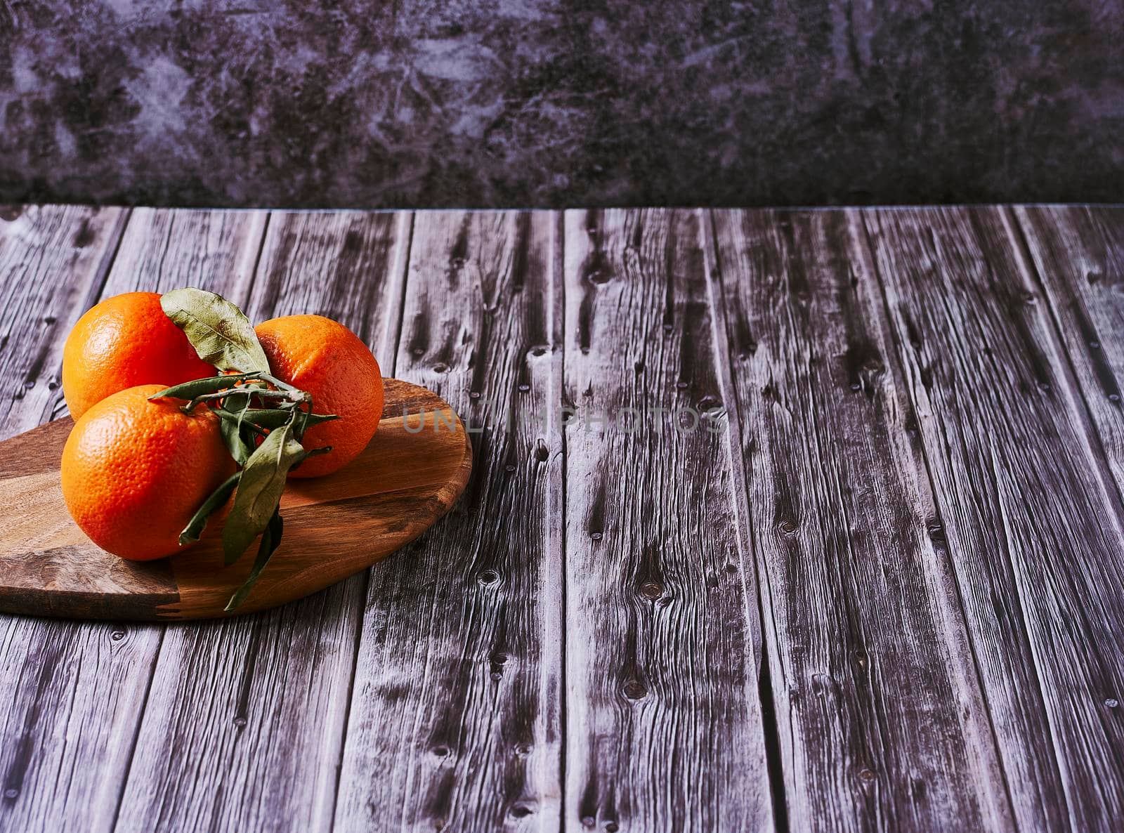 Various oranges on wooden table on wooden floor and stone background