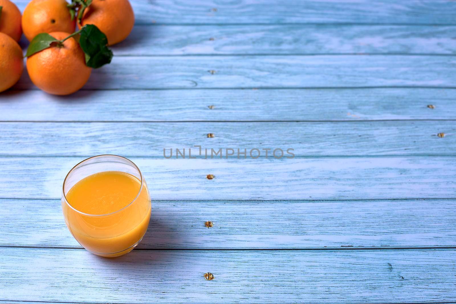 Glass of orange juice with whole oranges by raul_ruiz