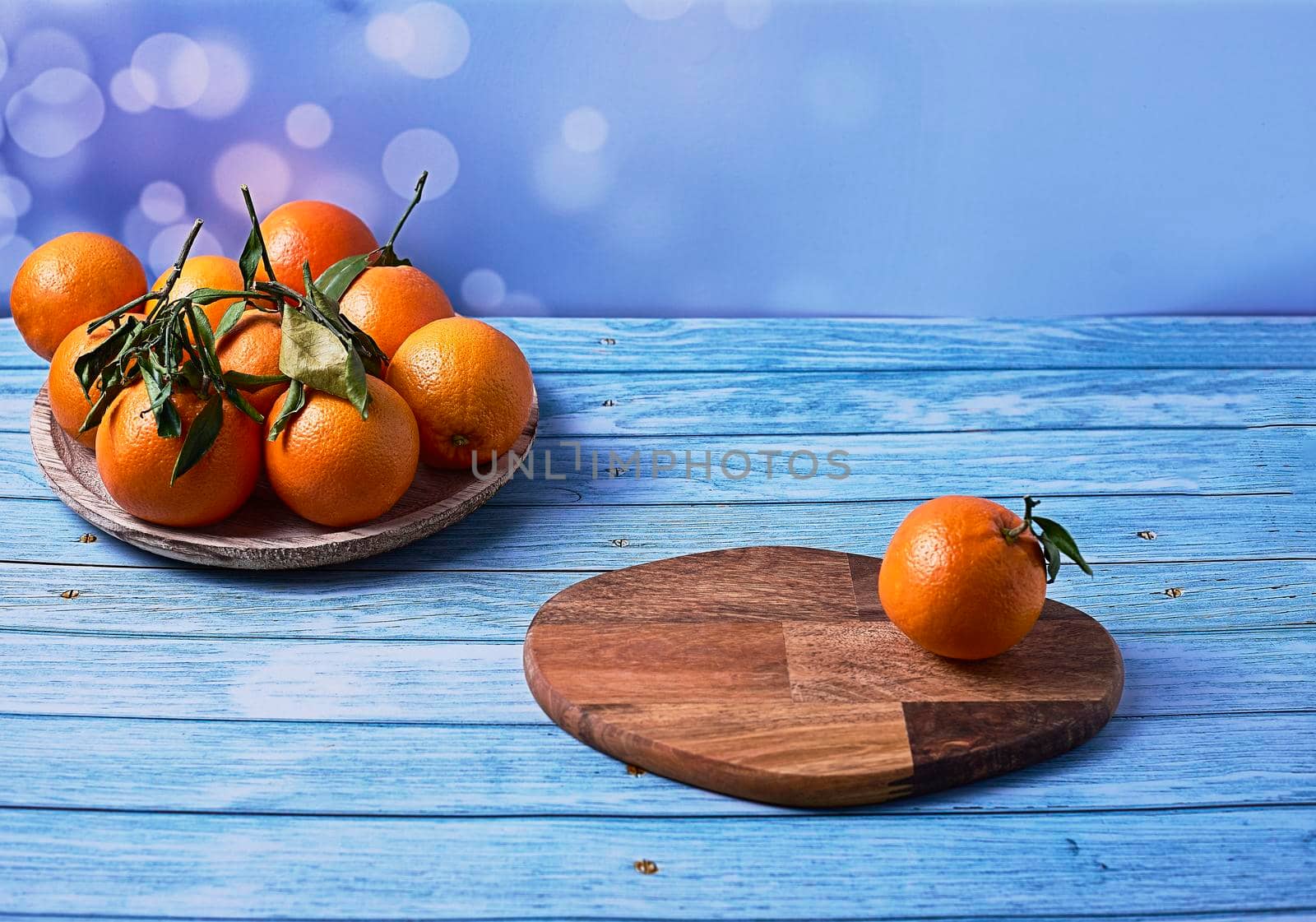 Orange on wooden board and group of oranges on wooden plate on bright background and wooden floor