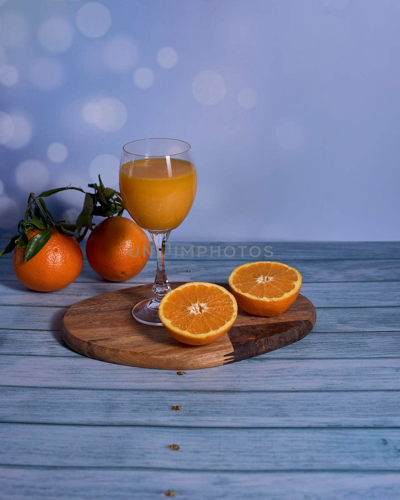 Glass of orange juice on wooden table, half orange and whole oranges, wooden floor, bright sound