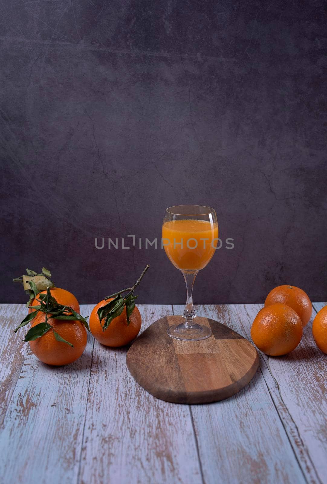 Glass of orange juice on wooden table with various oranges marble background wooden floor